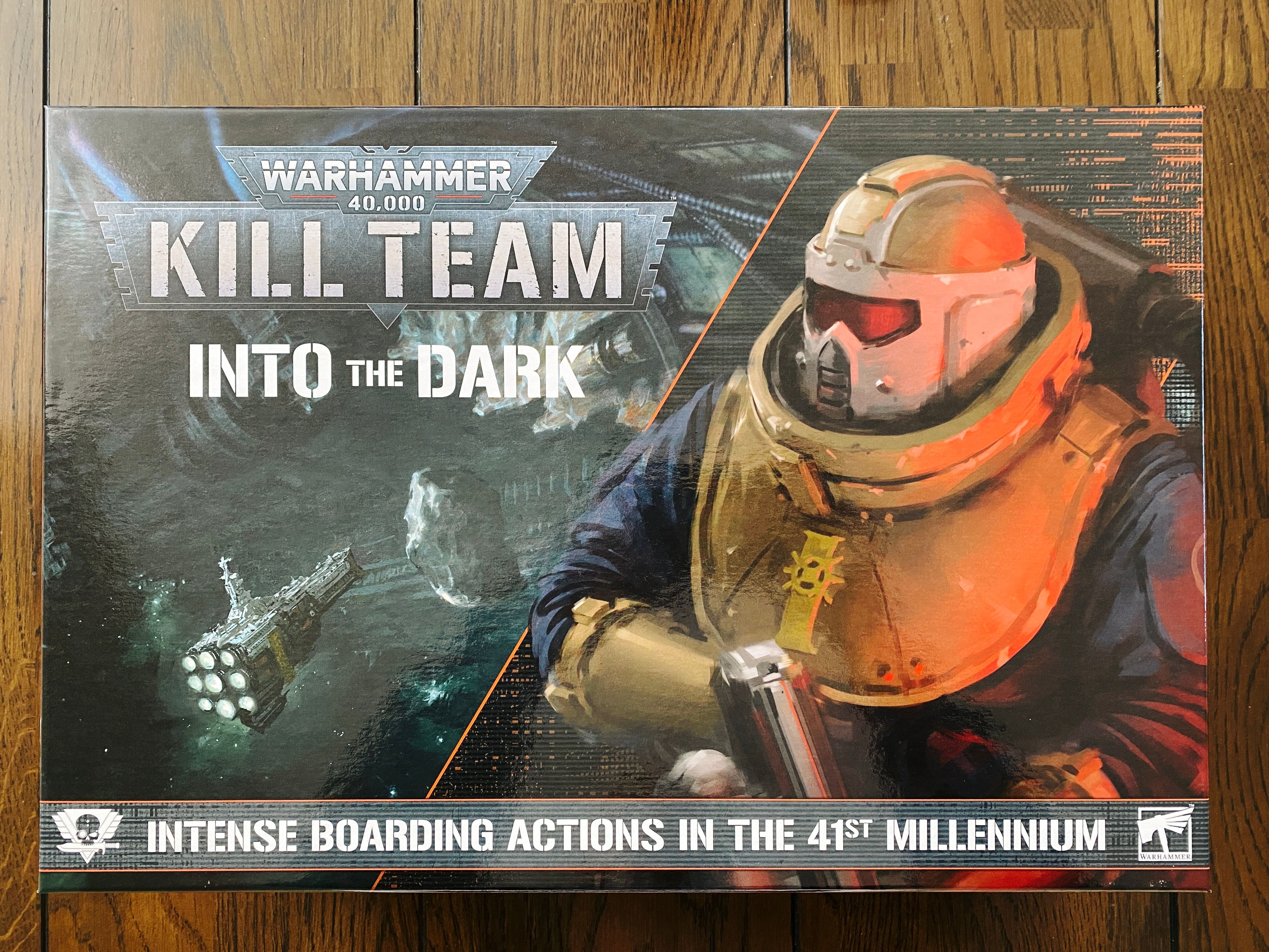 A photo of the (ENORMOUS) box of the new edition of Warhammer 40,000: Kill Team. The box art has a painting of a huge cathedral-like starship floating in the depths of space on the left-hand side, and on the right is a heavily armed and armoured guy in a chonky helmet holding what looks like a beefy shotgun. The tagline for this is "Intense boarding actions in the 41st millennium."