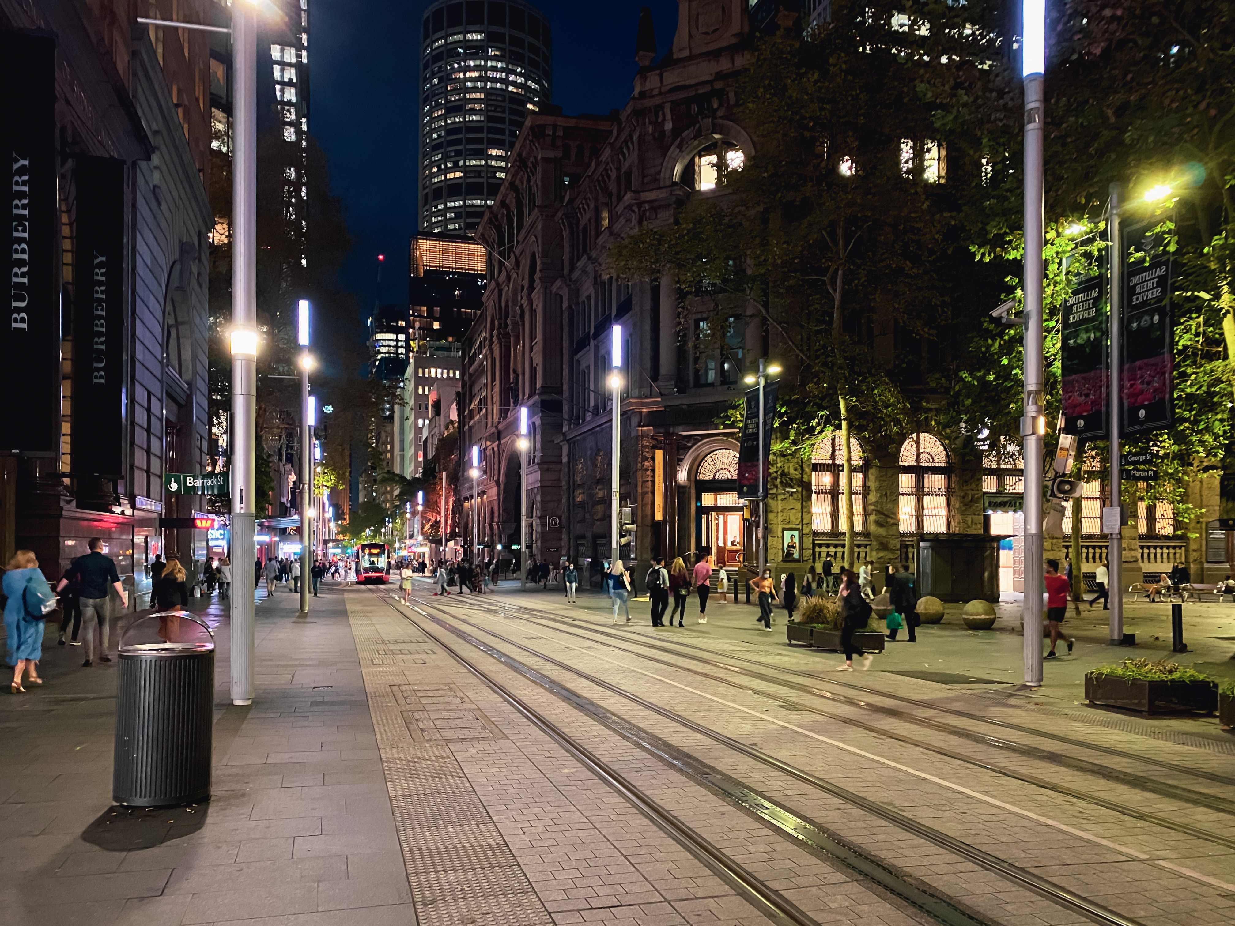 A photo looking down George St in Sydney. Tram tracks run down the middle of the road, there's people everywhere, and the buildings are a mix of old and new.