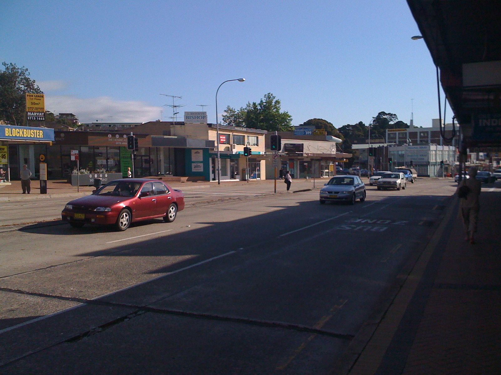 A photo of a six-lane road (three in each direction), with cars driving down it. The road is concrete rather than asphalt, and the buildings visible on the other side of the road are a bit run-down-looking.