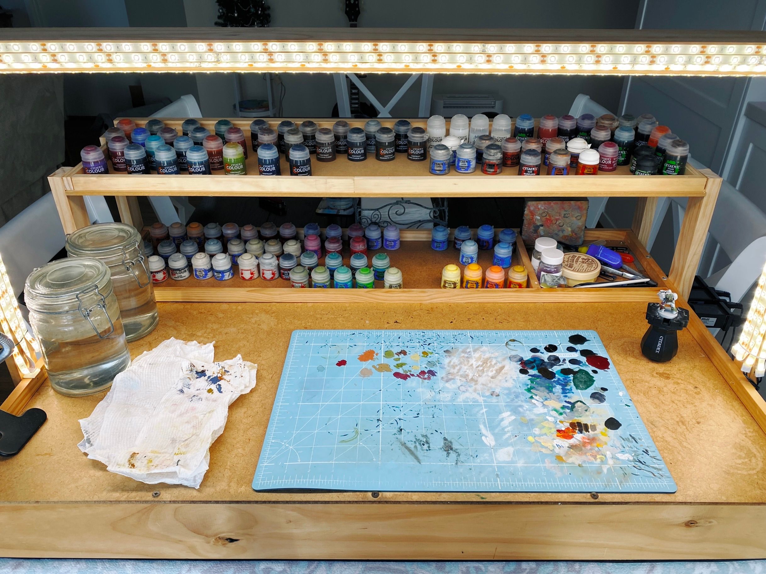 A photo of my DIY painting table that sits on the dining room table. There's a section at the back that all the paints live in, and there's now a second level above it so I can spread the paints out now.