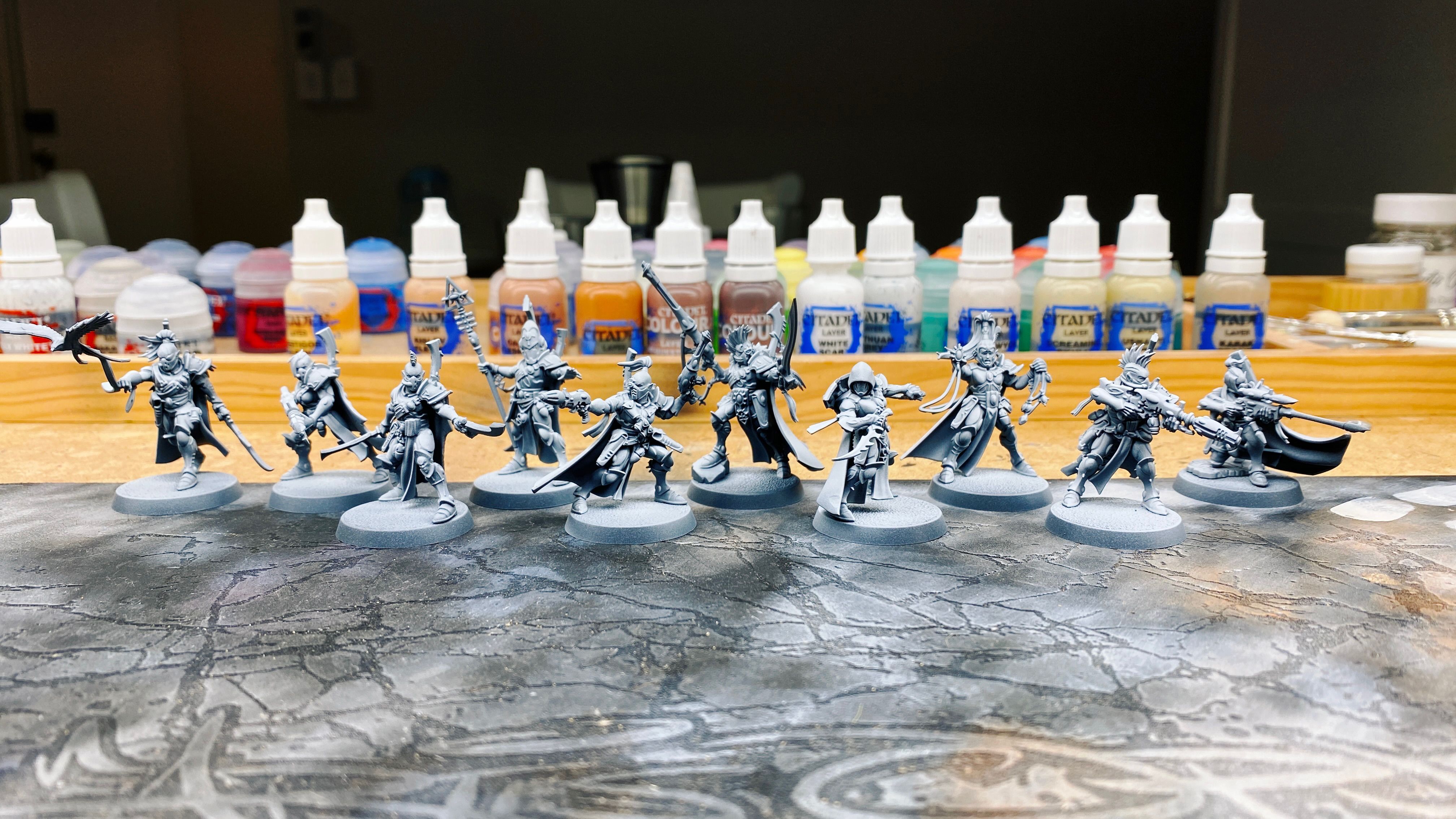 A photo of ten undercoated miniatures. Their armour is all quite elegant-looking as befits space elves, but they've got a lot of little details that make them look more like pirates. Everyone has a cool cloak, and the majority of them have very punk-looking haircuts (undercuts, mohawks, topknot ponytails) and are wearing rebreathers. Their poses are all mid-action.