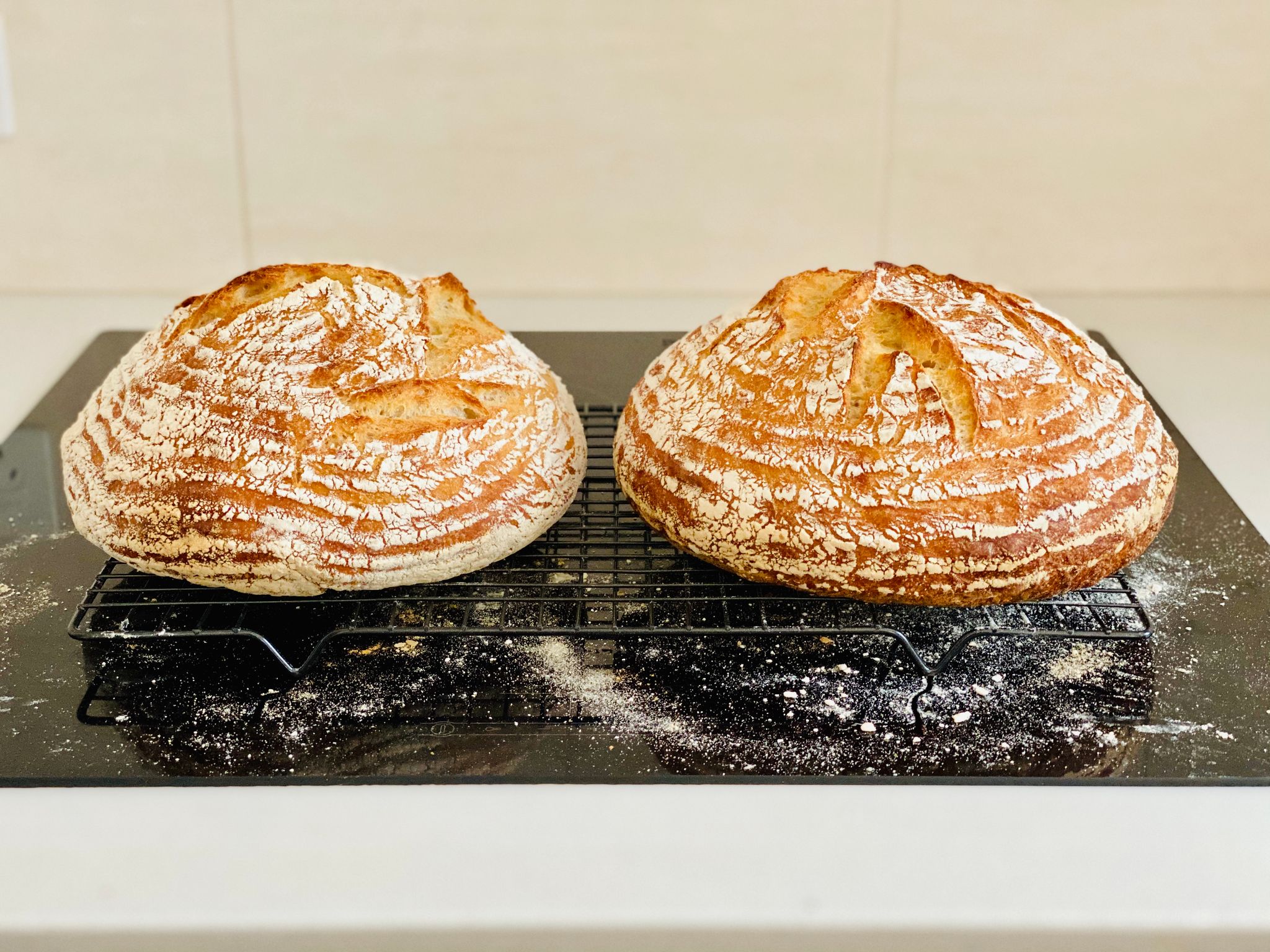 A photo of two round golden-brown loaves of bread sitting on a cooling rack.