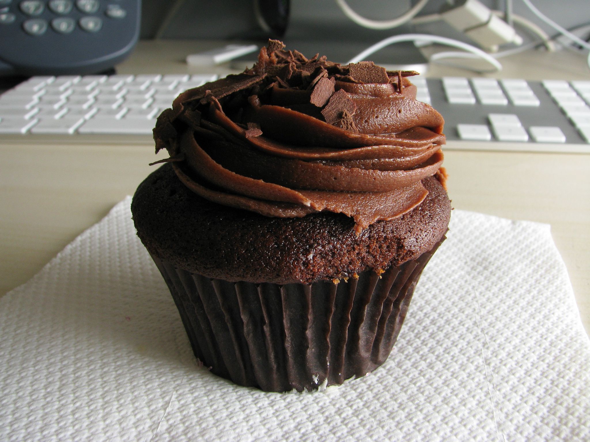 A close-up photo of a chocolate cupcake with a swirl of chocolate icing on the top.