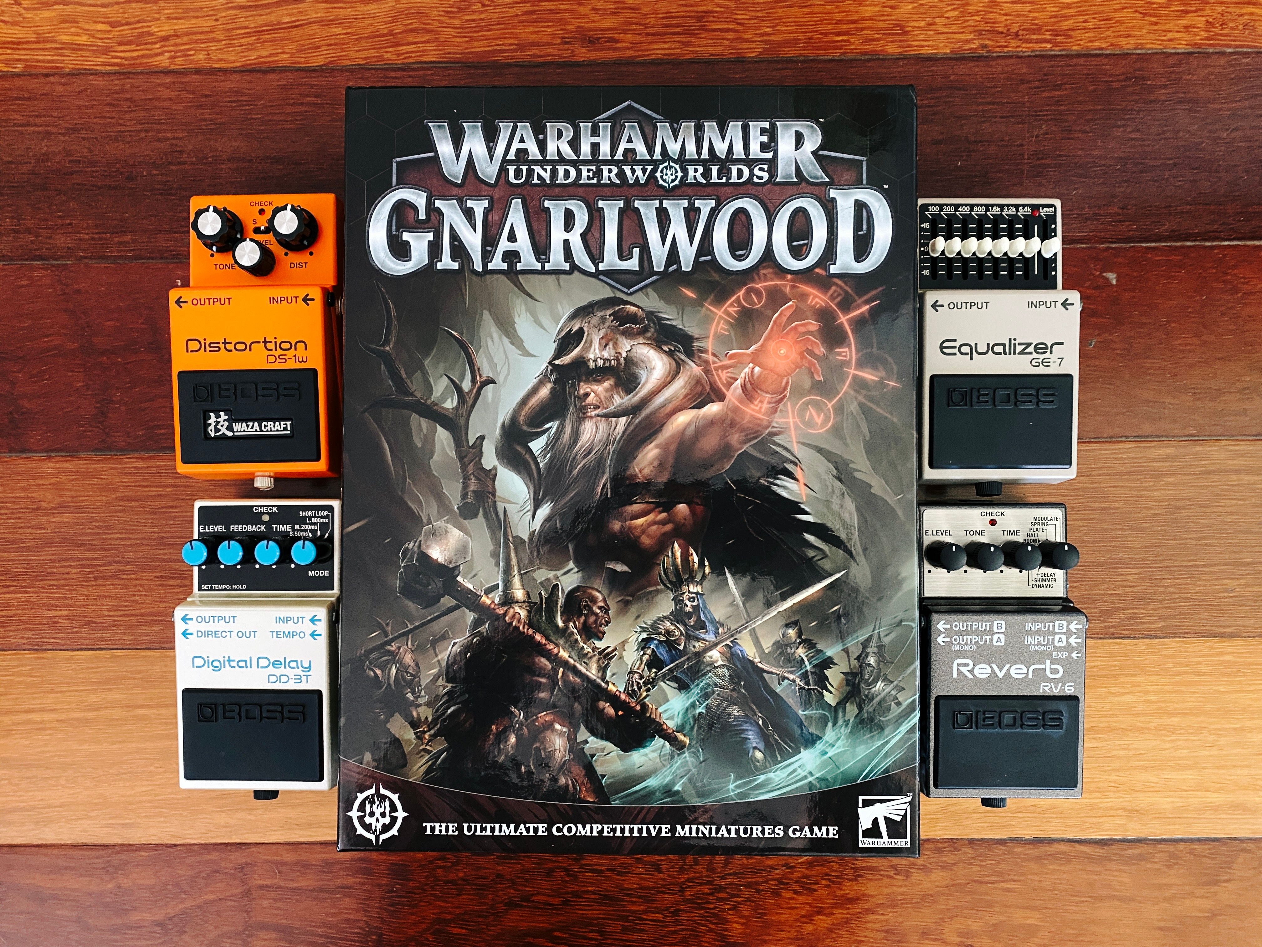 A photo of the box of Games Workshop's new Warhammer Underworlds box, "Gnarlwood", and four Boss guitar pedals. The Underworlds box has artwork of a guy in furs and looking very shamanic, and the guitar pedals are the DS-1W distortion, DD-3T digital delay, GE-7 equaliser, and Reverb RV-6.