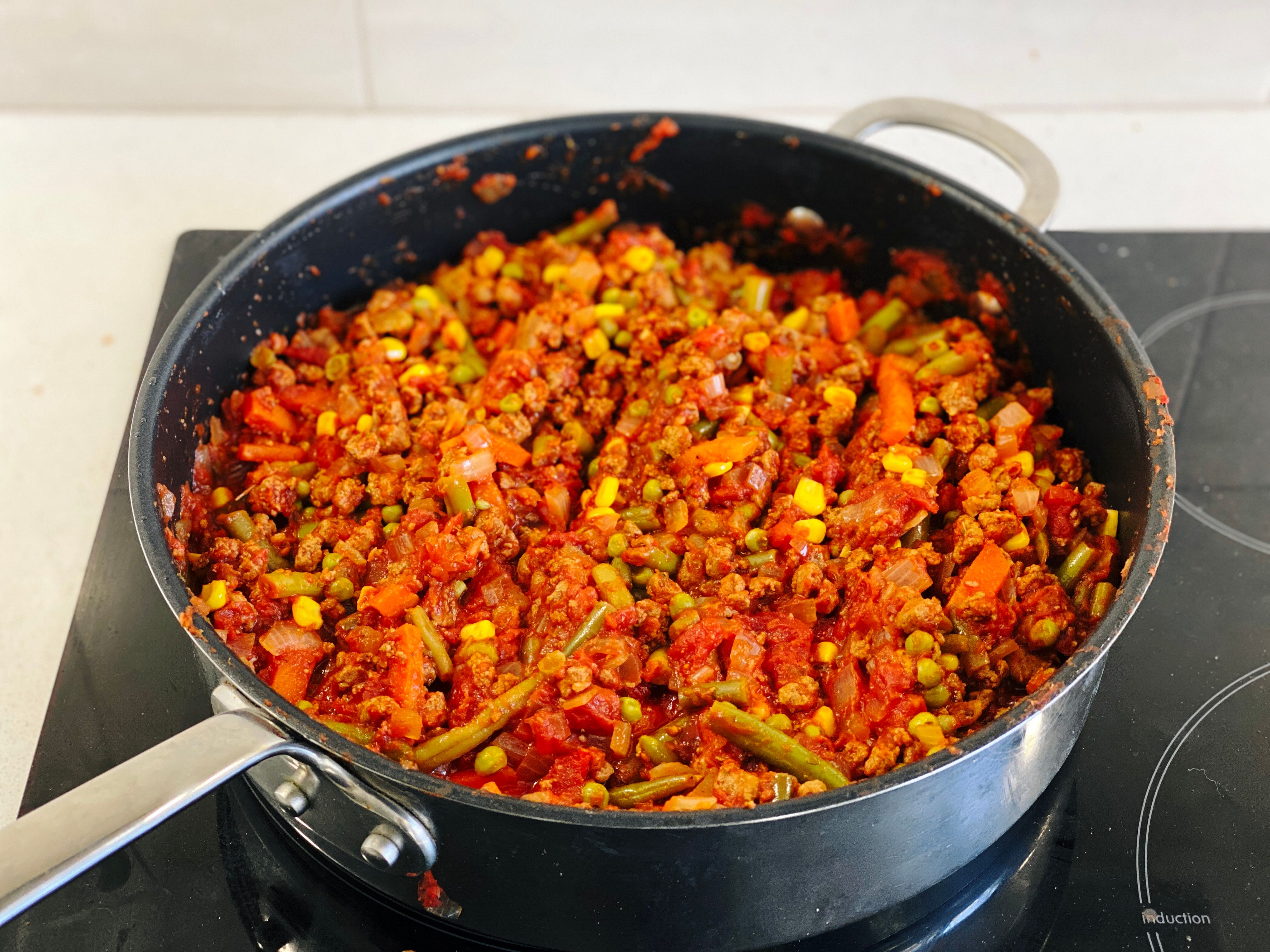 A big batch of vegetable bolognese sauce simmering in a large frying pan. There's diced onion, corn, peas, beans, and carrots in it as well as the Quorn (which looks pretty much just like beef mince).