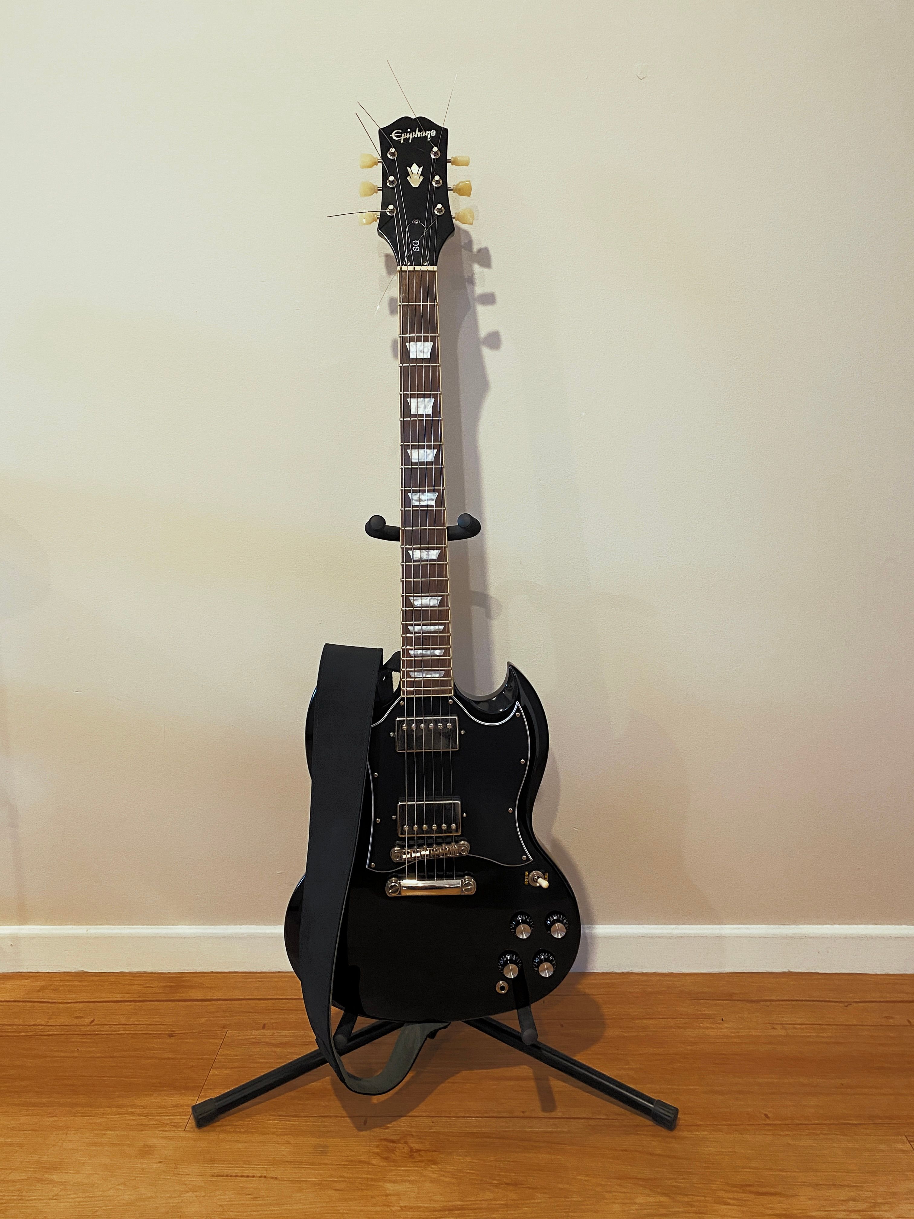 A photo of a shiny black electric guitar sitting on a guitar stand.