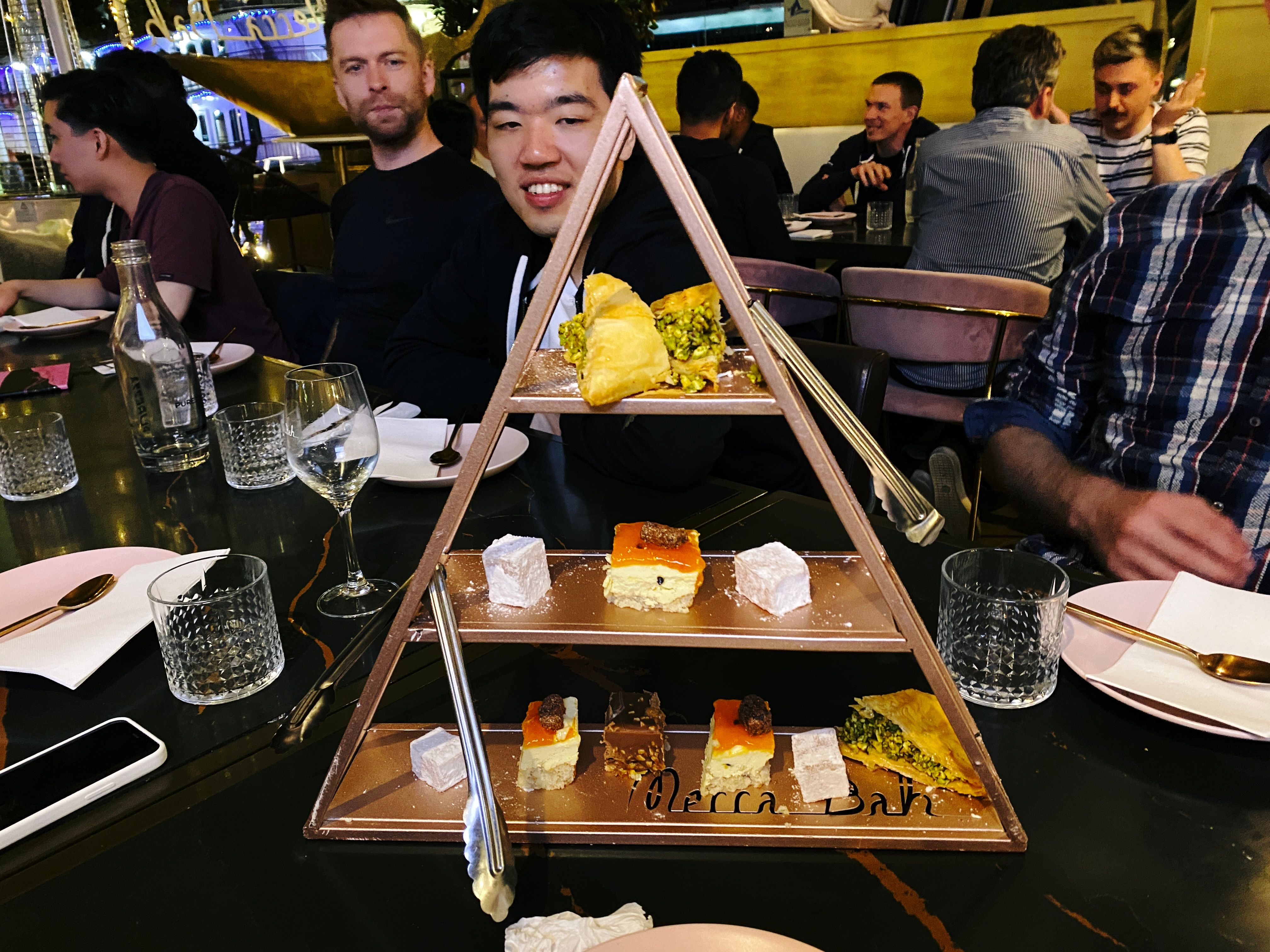 A photo of triangular stand in the middle of the table, with three levels and little nibbly desert things on it. There's some Turkish delight, some pastry thing, a couple of little bits of cheese cake, and a piece of chocolate something or other that I had and was delicious.