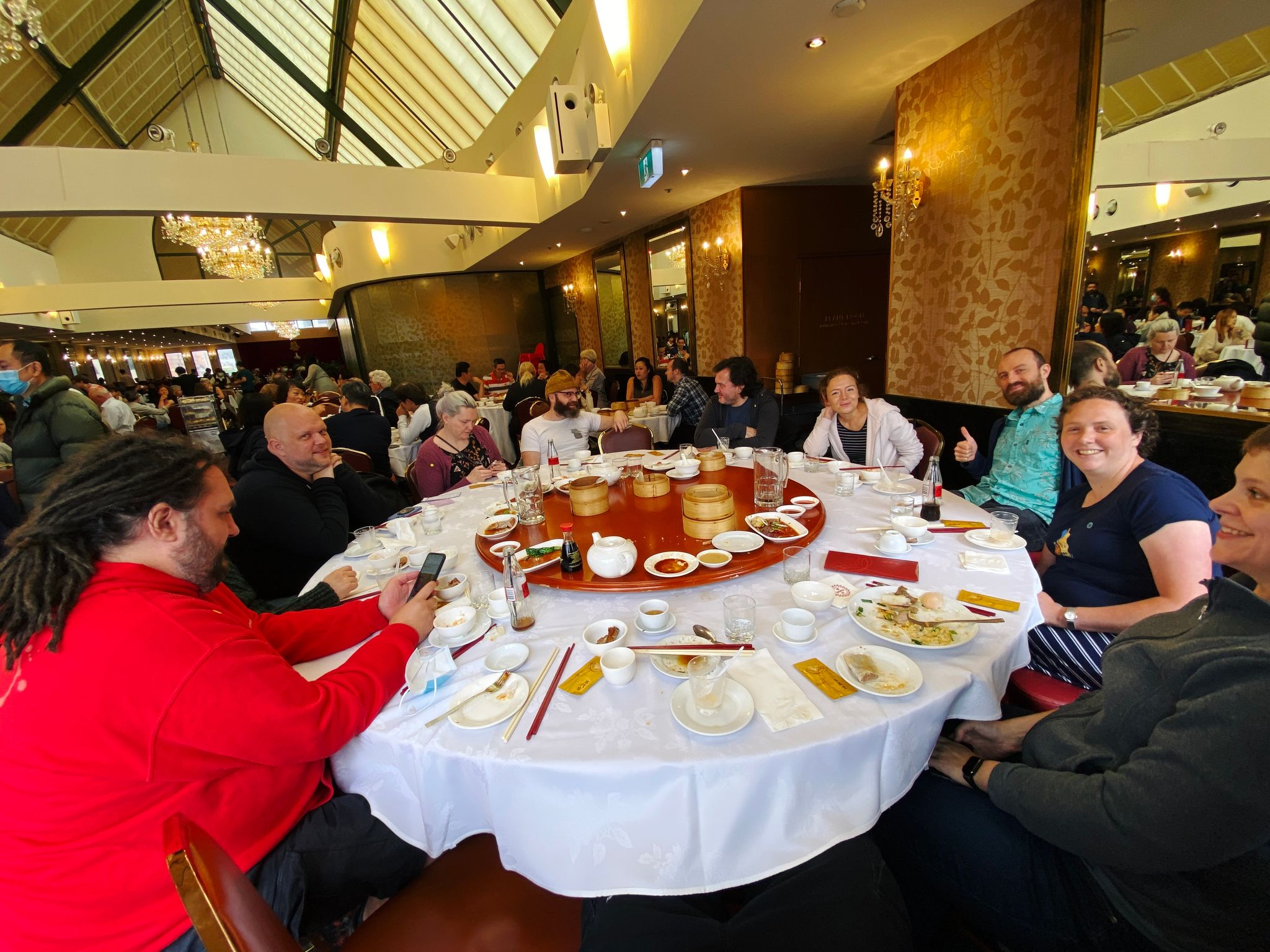 A photo of eleven people sitting around a big round table, with lots of empty plates and steamer baskets in the middle.