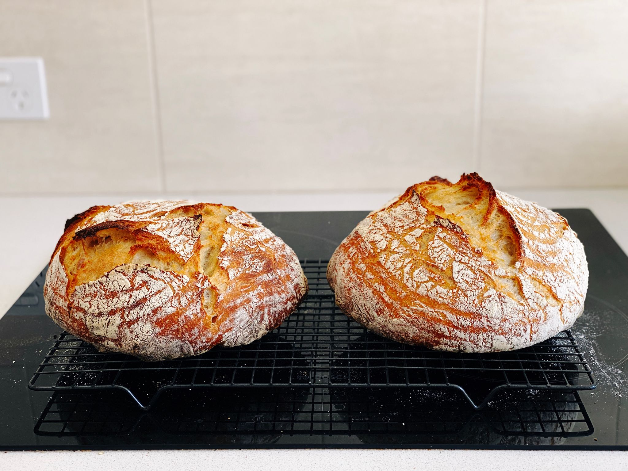 Two round golden brown loaves of bread sitting on a cooling rack.