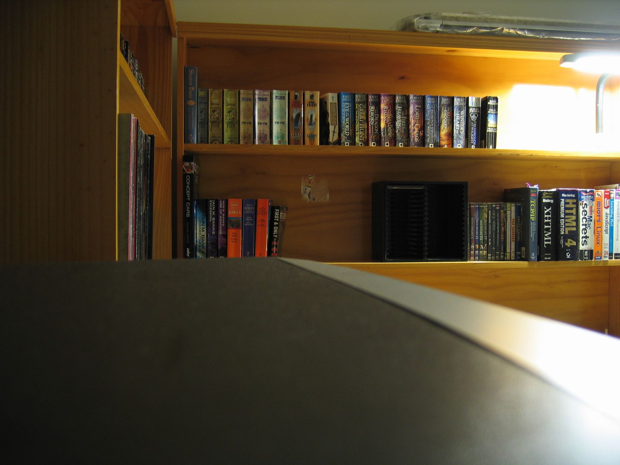 A photo of a bookshelf, taken with the camera sitting on top of a CRT TV, and the TV is taking up the bottom third of the photo.