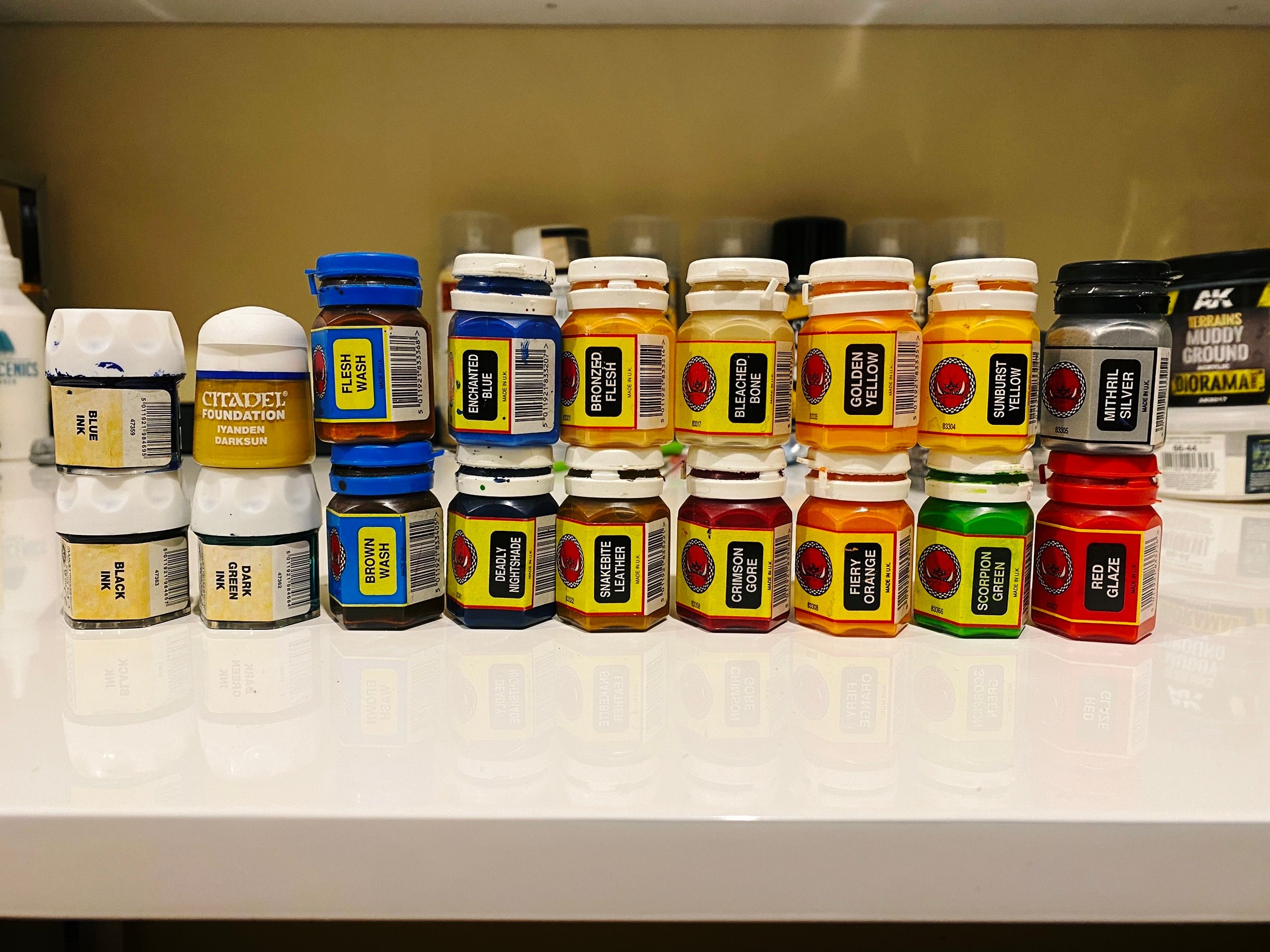 A photo of fourteen of the REALLY old mid-90s hexagonal-shaped paint pots from Games Workshop in various colours, along with three inks from the slightly newer screwtop type, and one from the slightly newer again round pop-top type.
