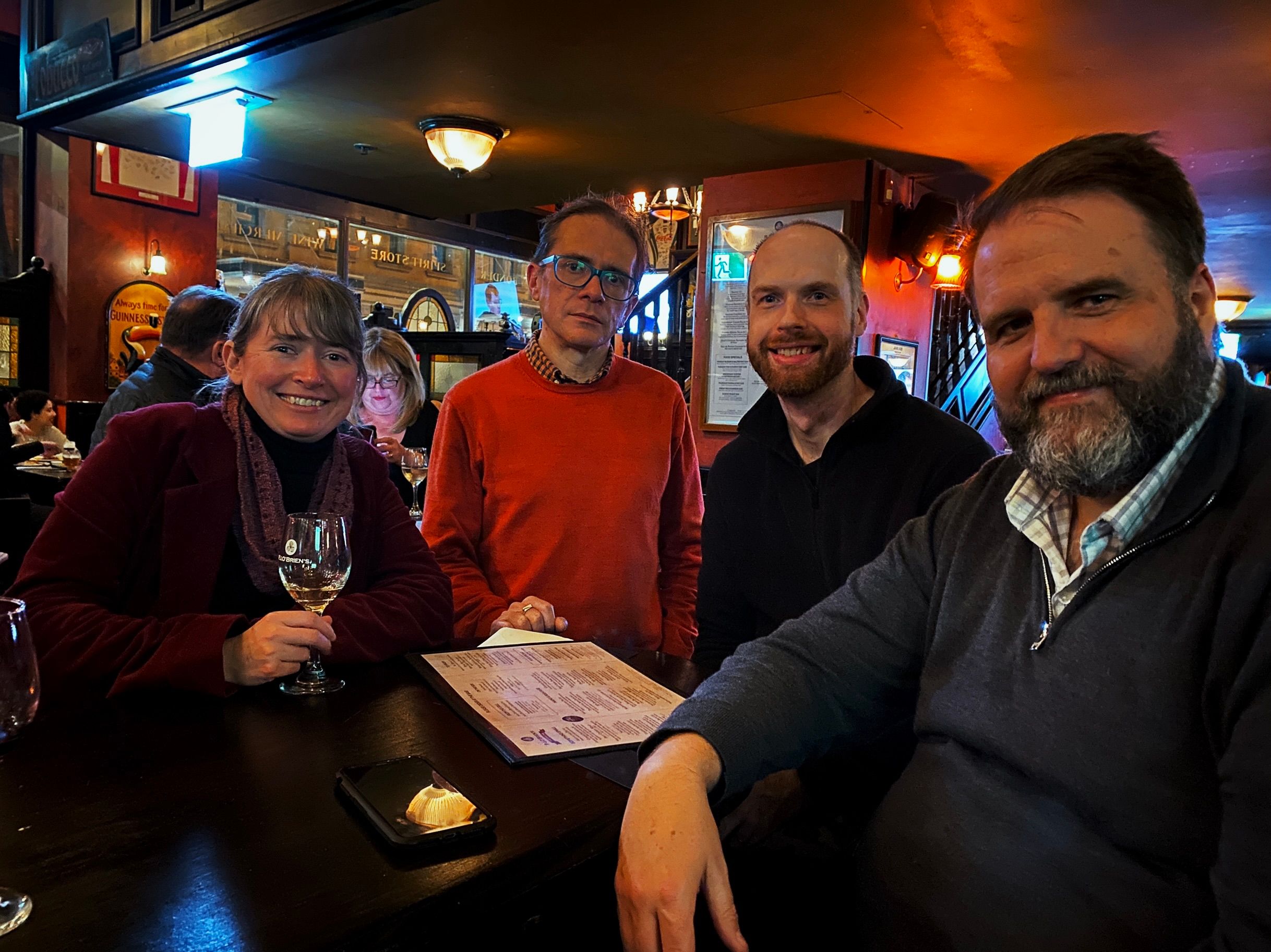 A photo of four people sitting in an Irish pub smiling at the camera.