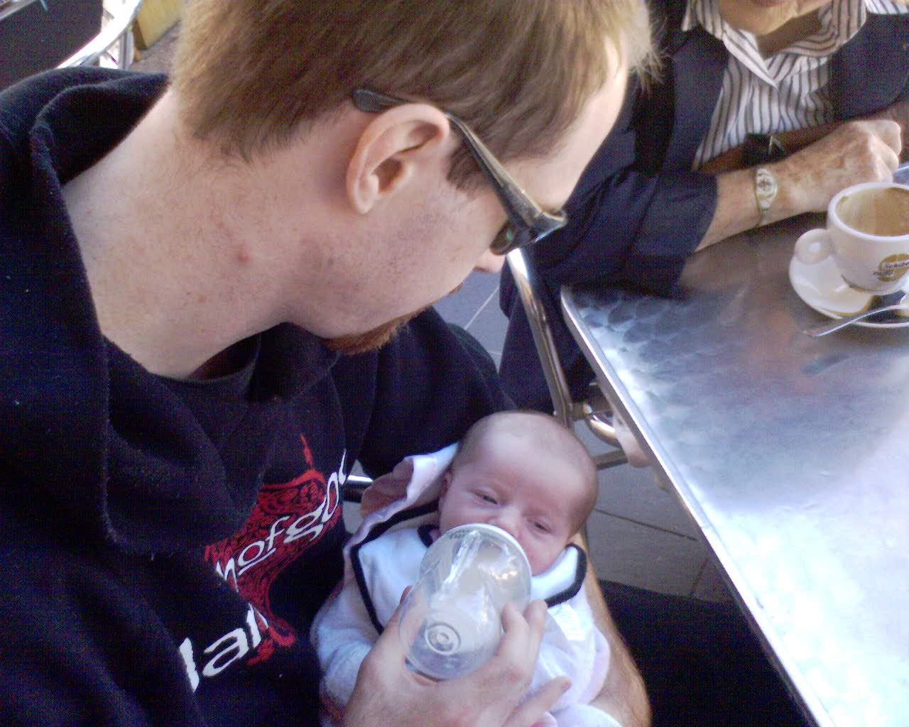 A photo of a tiny newborn baby being fed from a bottle. She's lying in my arms and has her eyes half-closed.