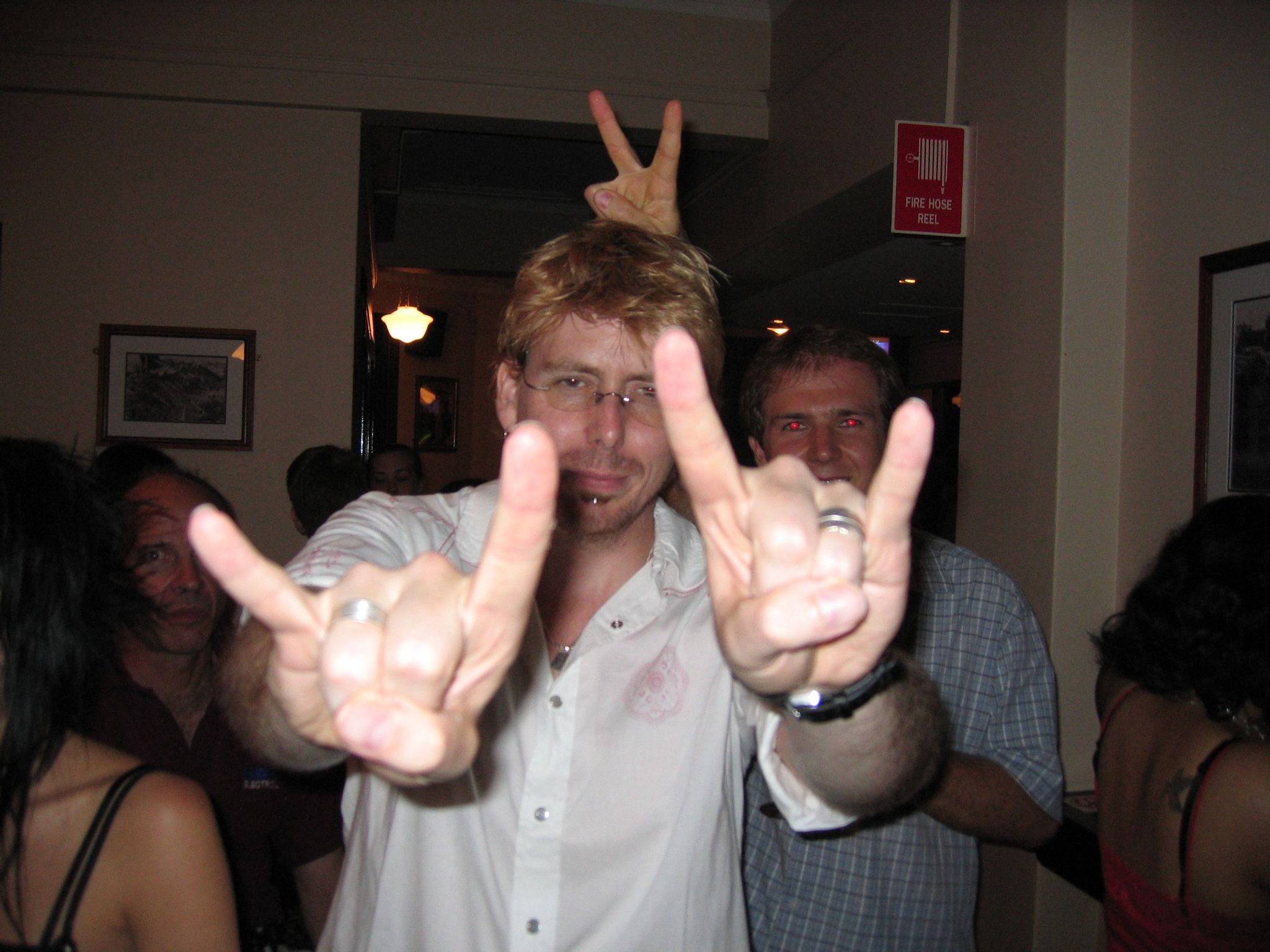 A photo of a man throwing the horns with both hands.