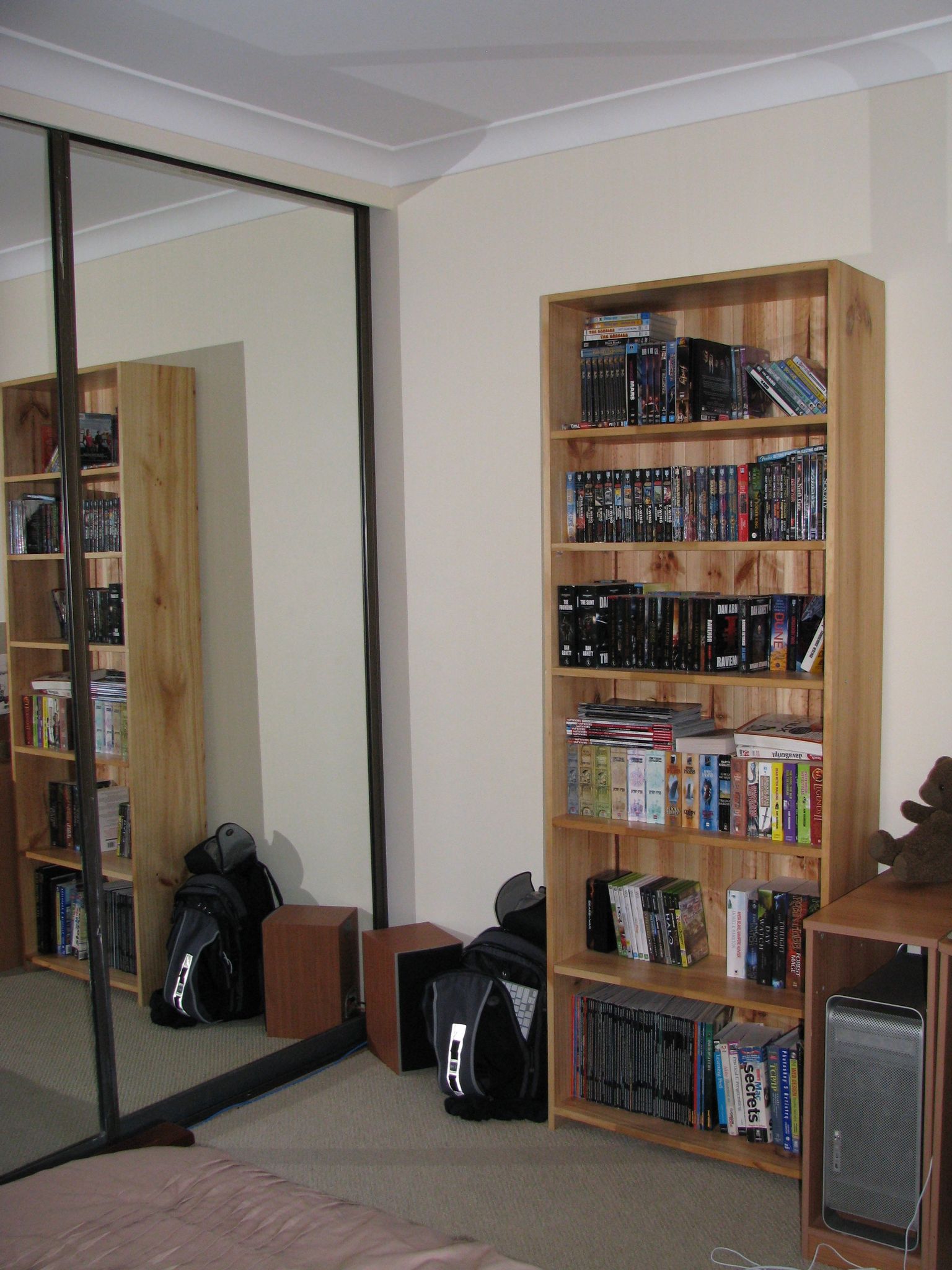 A photo of my room from the corner where the queen-size bed is. There's a mirrored closet door at the left and the bookshelf is clearly visible to the right of it along the wall.