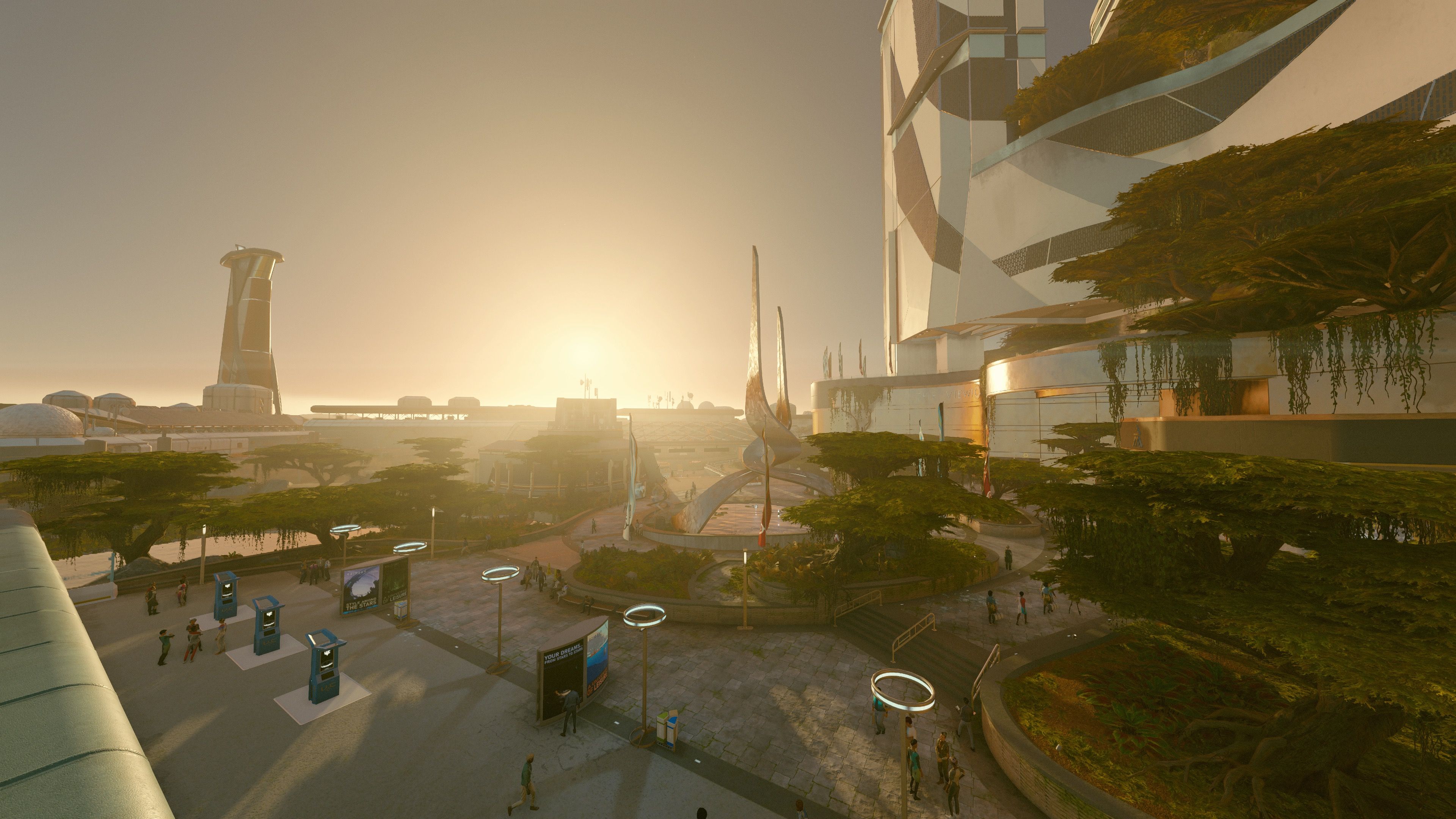 A screenshot from Starfield of the sunrise over, uh, one of the districts (I forget which one it was) on Jemison in the Alpha Centauri system. It's taken looking over an open public plaza with trees and people walking around, and there's tall, sleek, futuristic buildings as well.