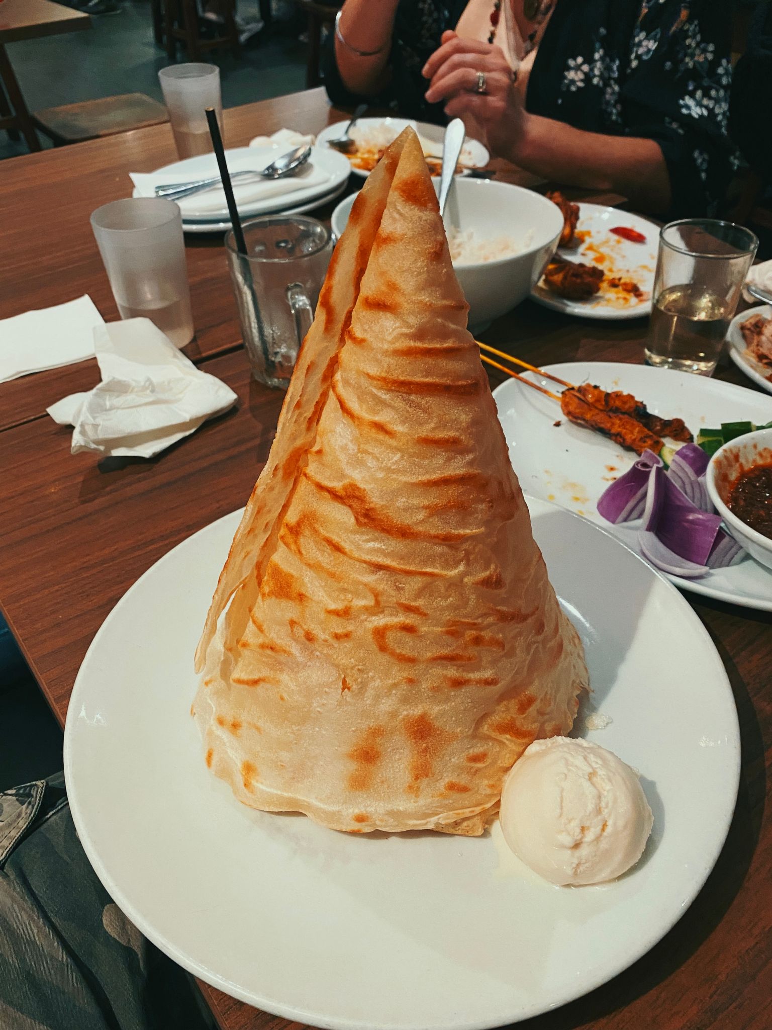 A photo of a roti tisu, which is a tall cone-shaped dessert roti that's covered in sugar and butter and is AMAZING.