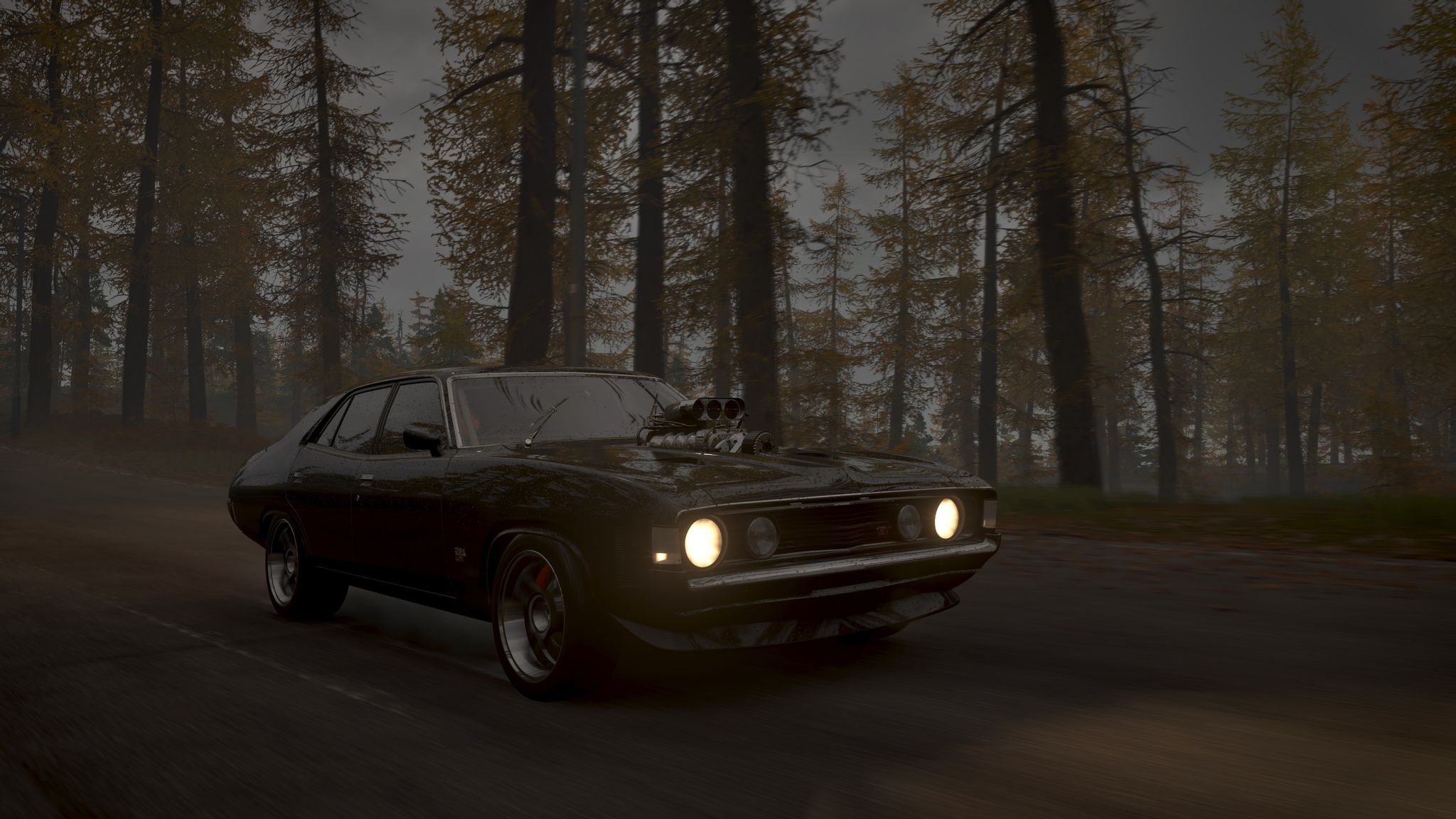 A screenshot from Forza Horizon 4 of a black Ford Falcon GT-HO with its headlights on and a big mechanical air intake poking out of the bonnet, Mad Max-style. It's fairly dark and the car is driving through a bunch of tall trees with grey sky visible through them.