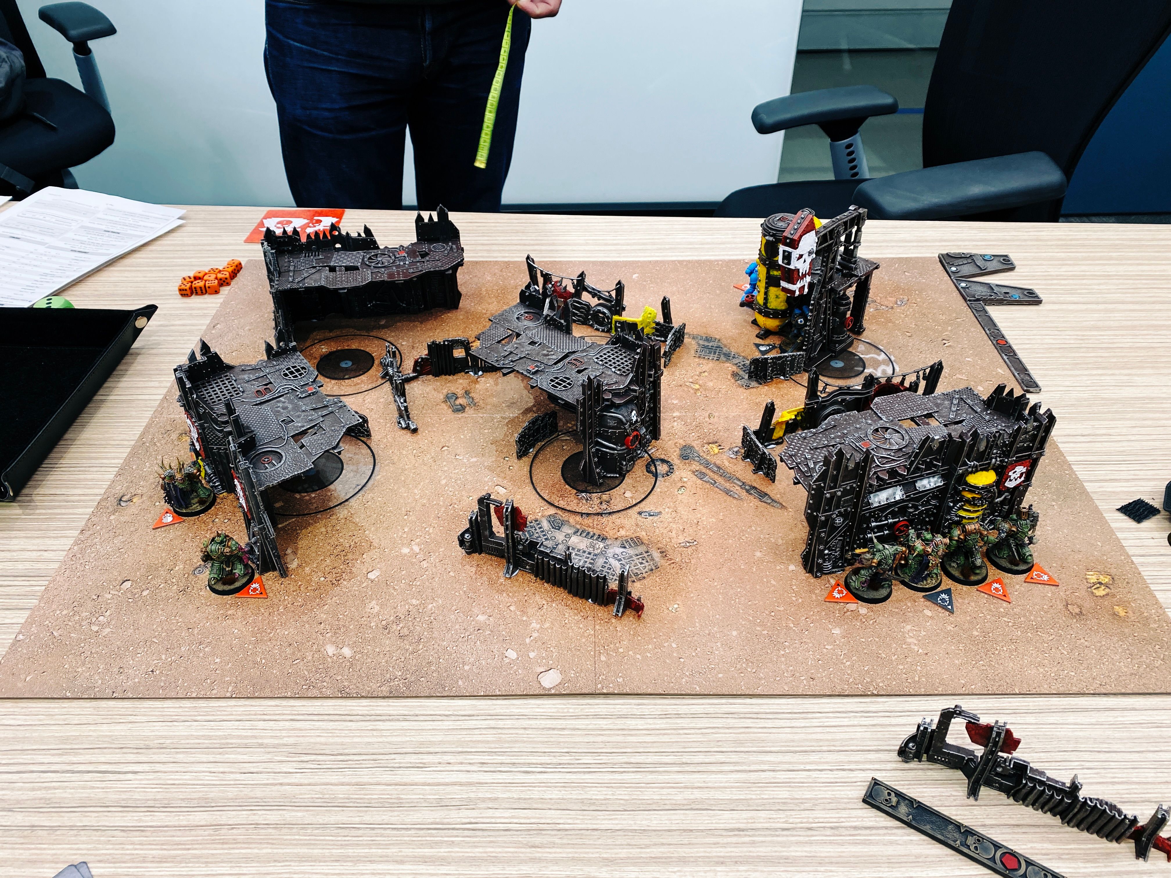 A photo of a game of Warhammer 40,000: Kill Team. It's on a gaming board with a bunch of junkyard-looking terrain, and on my side of the board are six green Death Guard Space Marines looking all gross and mutated.