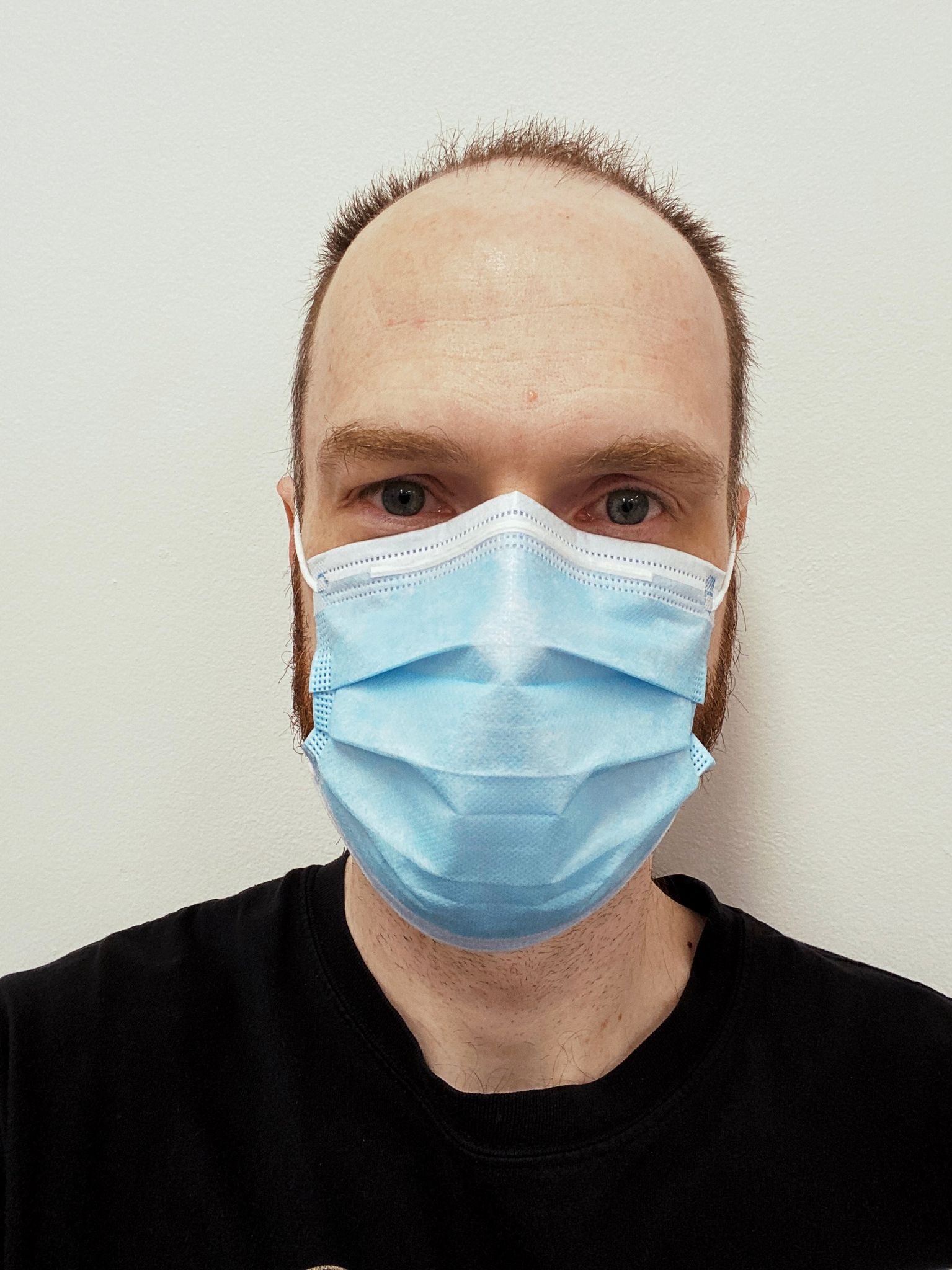 A selfie of me, a white man with short hair and, uh, let's call it a very large forehead, wearing a blue surgical mask.