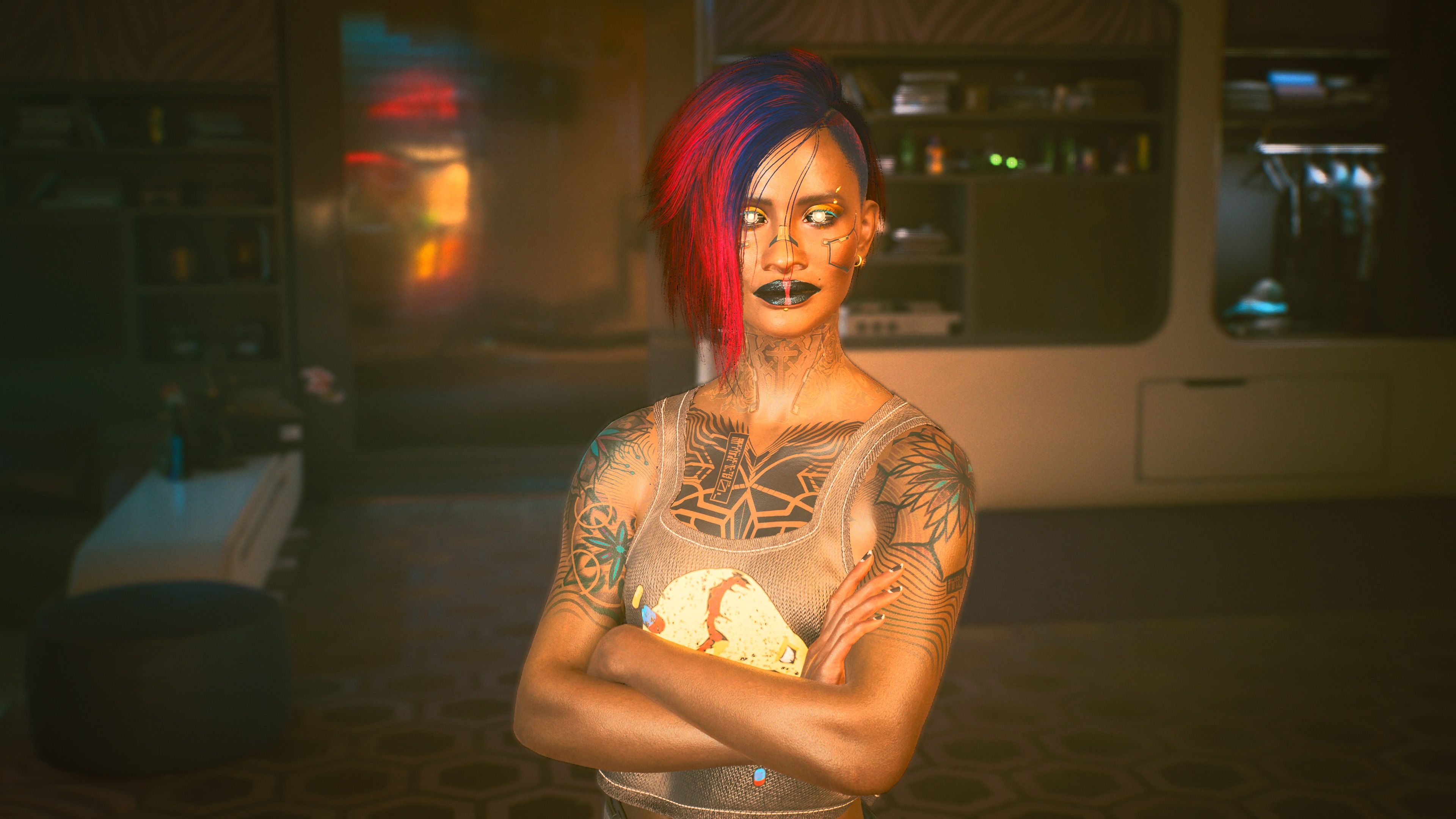 A screenshot of my character in the video game Cyberpunk 2077. She's Black and has purple/blue hair on one side of her head, with the other side shaved, she's got lots of tattoos on her chest and arms, and her eyes are glowing cybernetics. She has some electronic inlays in the skin on her face, and she's wearing black lipstick. She's standing with her arms crossed and a look of satisfaction on her face.