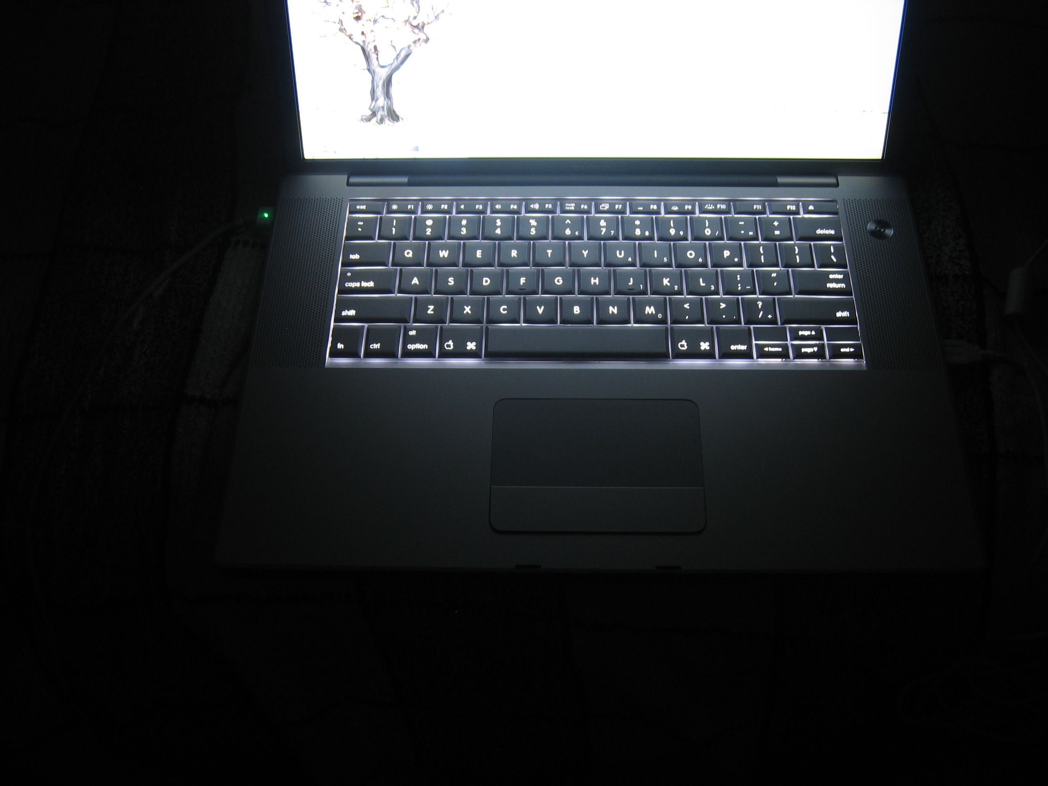 A photo of the keyboard of a MacBook Pro taken in the dark showing off the backlit keyboard.