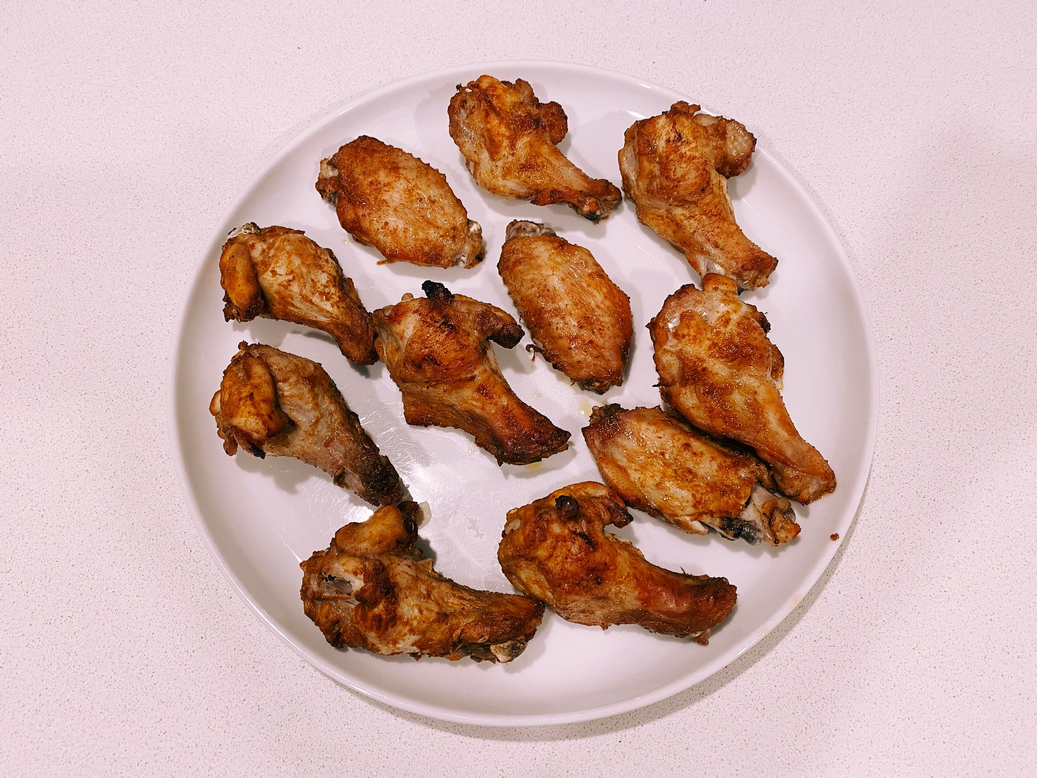 A photo of a plate with delicious-looking chicken wings on it.