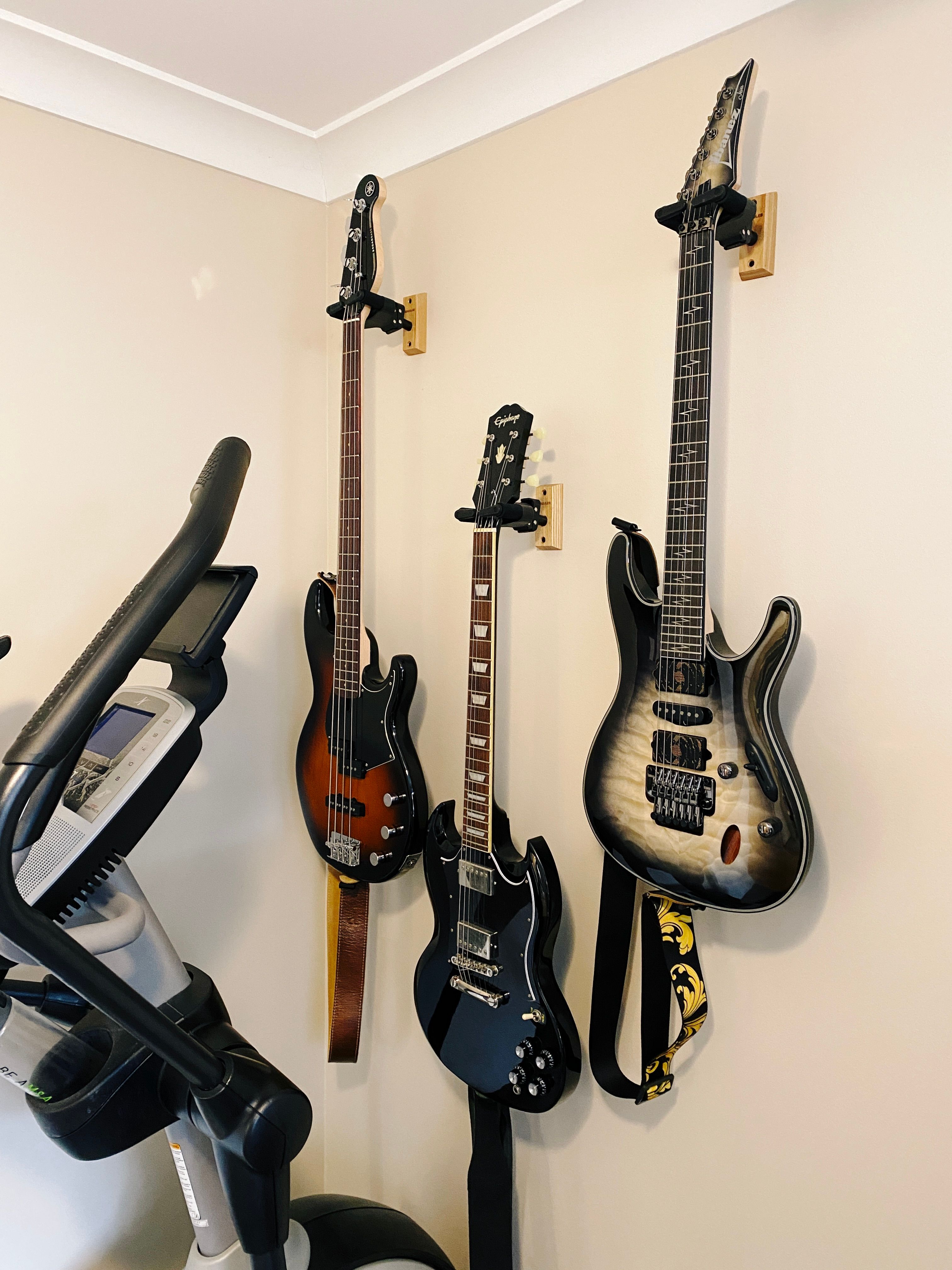 A photo of three guitars hanging on a wall.