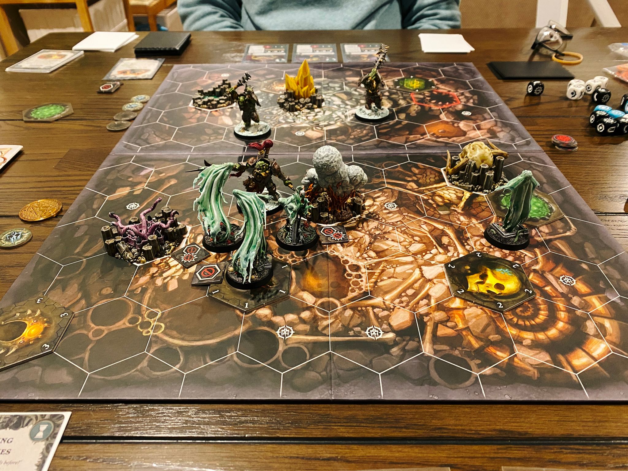 A photo of a Warhammer Underworlds board, with tiled hexes on it. Lady Harrow's Mournflight are at the front, consisting of four flowing ghostly-looking spirits. Facing them are Morgok's Krushas, three heavily armed and armoured orruks (orks).
