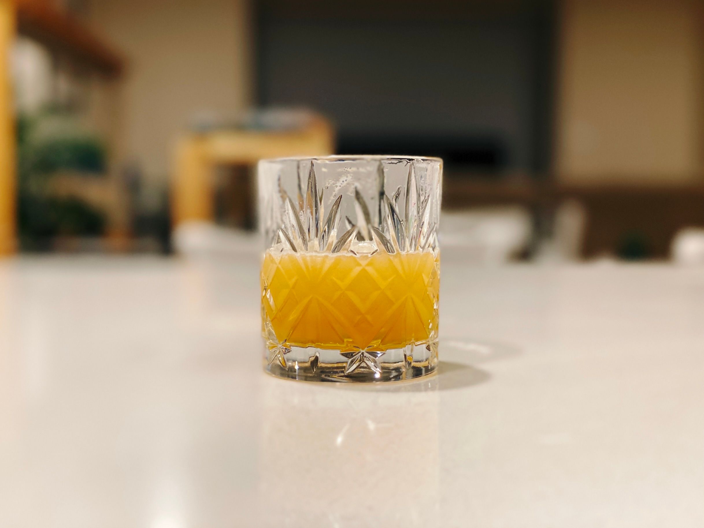 A photo of a golden-looking drink in a fancy whisky glass.