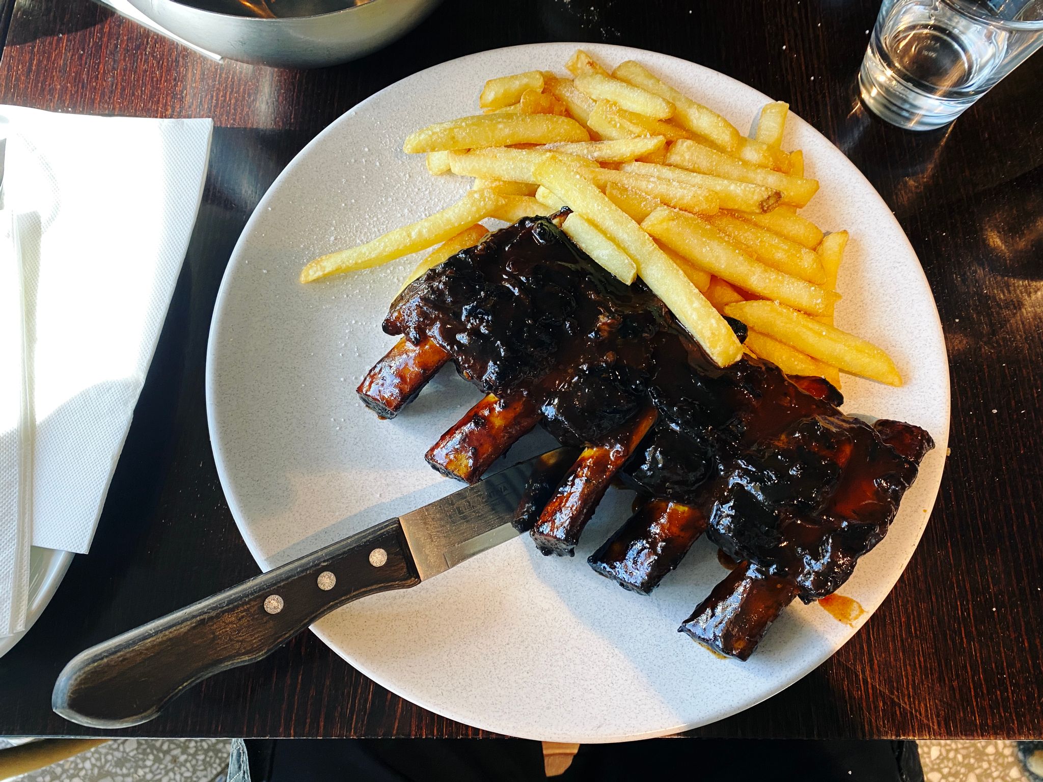 A photo of a plate with chips and a half rack of beef ribs in it.