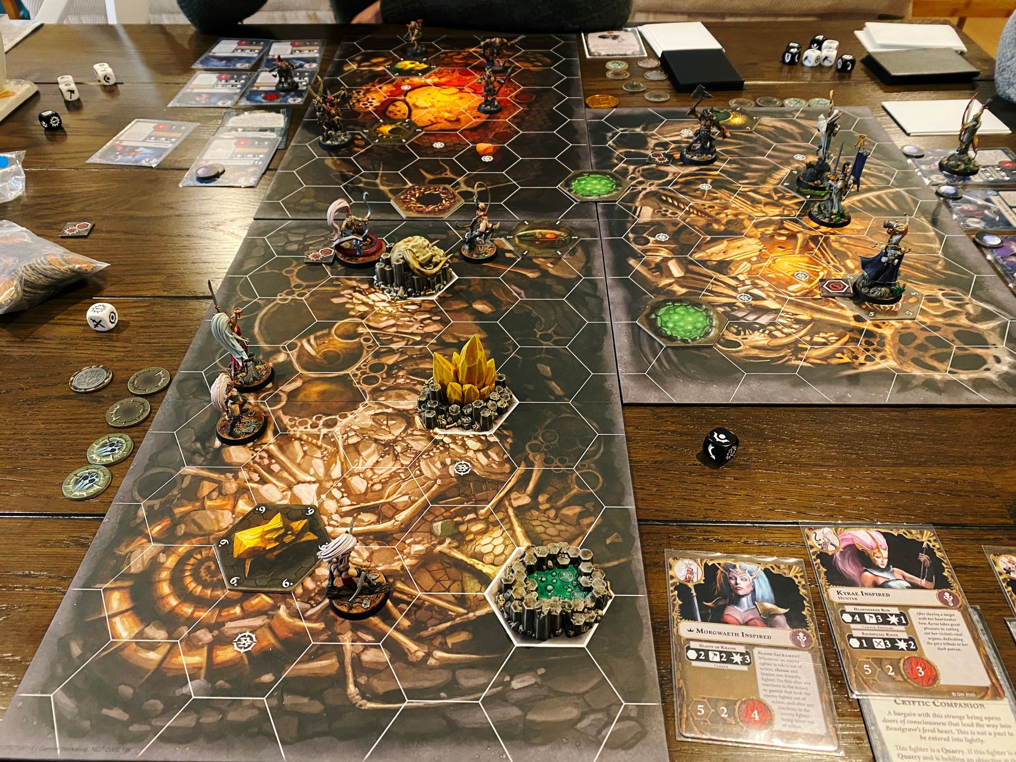 A photo of the board setup of a three-player game of Warhammer Underworlds, with all the miniatures set up in their starting positions but with the game not having started yet.