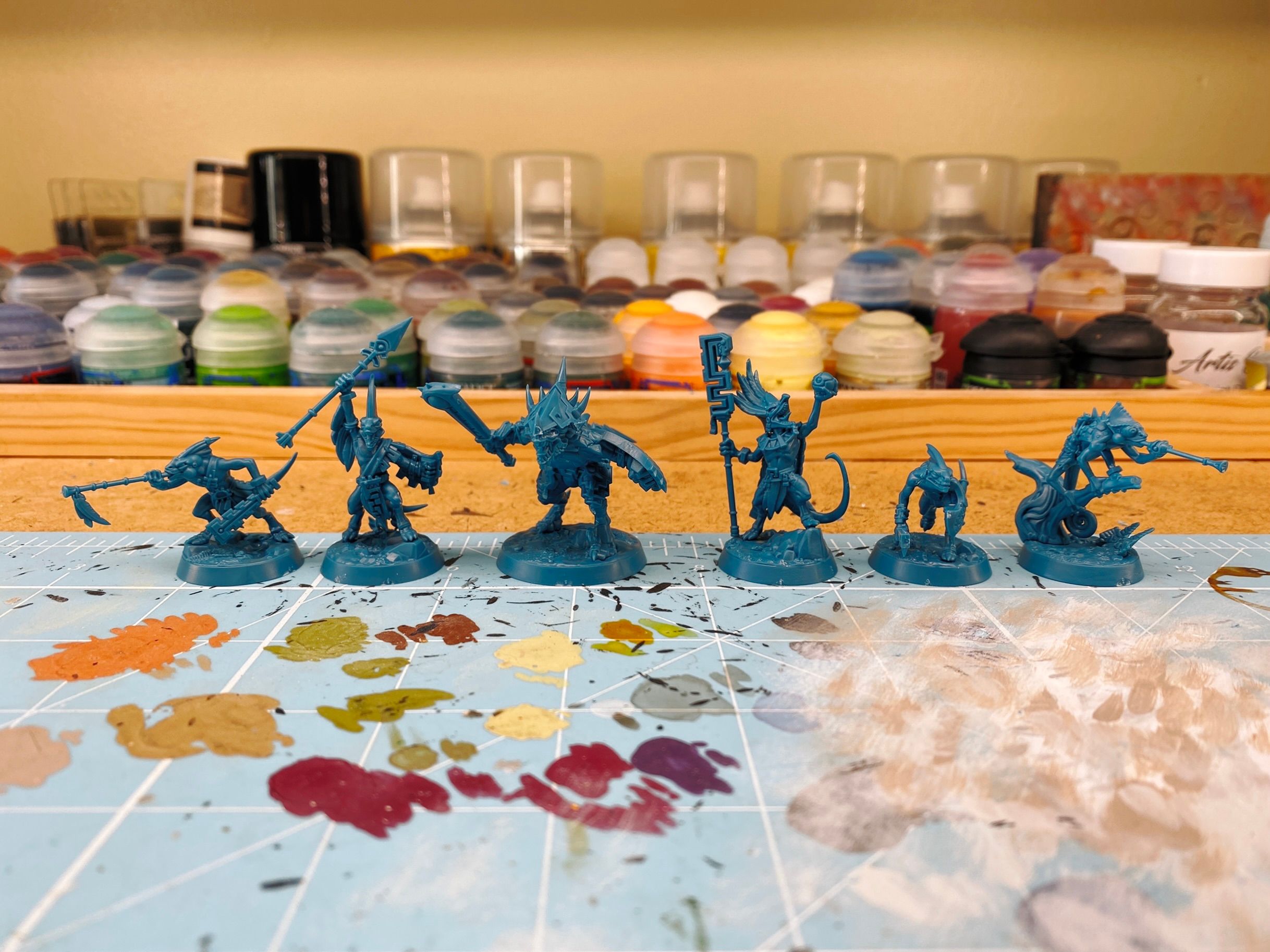 A photo of the Starblood Stalkers warband assembled, in torquoise-coloured plastic. Six miniatures, all lizards. One has a blowpipe, another has a spear raised above his head, the third is slinking along. Another is a chameleon with a blowpipe, the fifth has an elaborate staff and is holding a small ball up in triumph, and the last is a big heavily-armoured chonker.