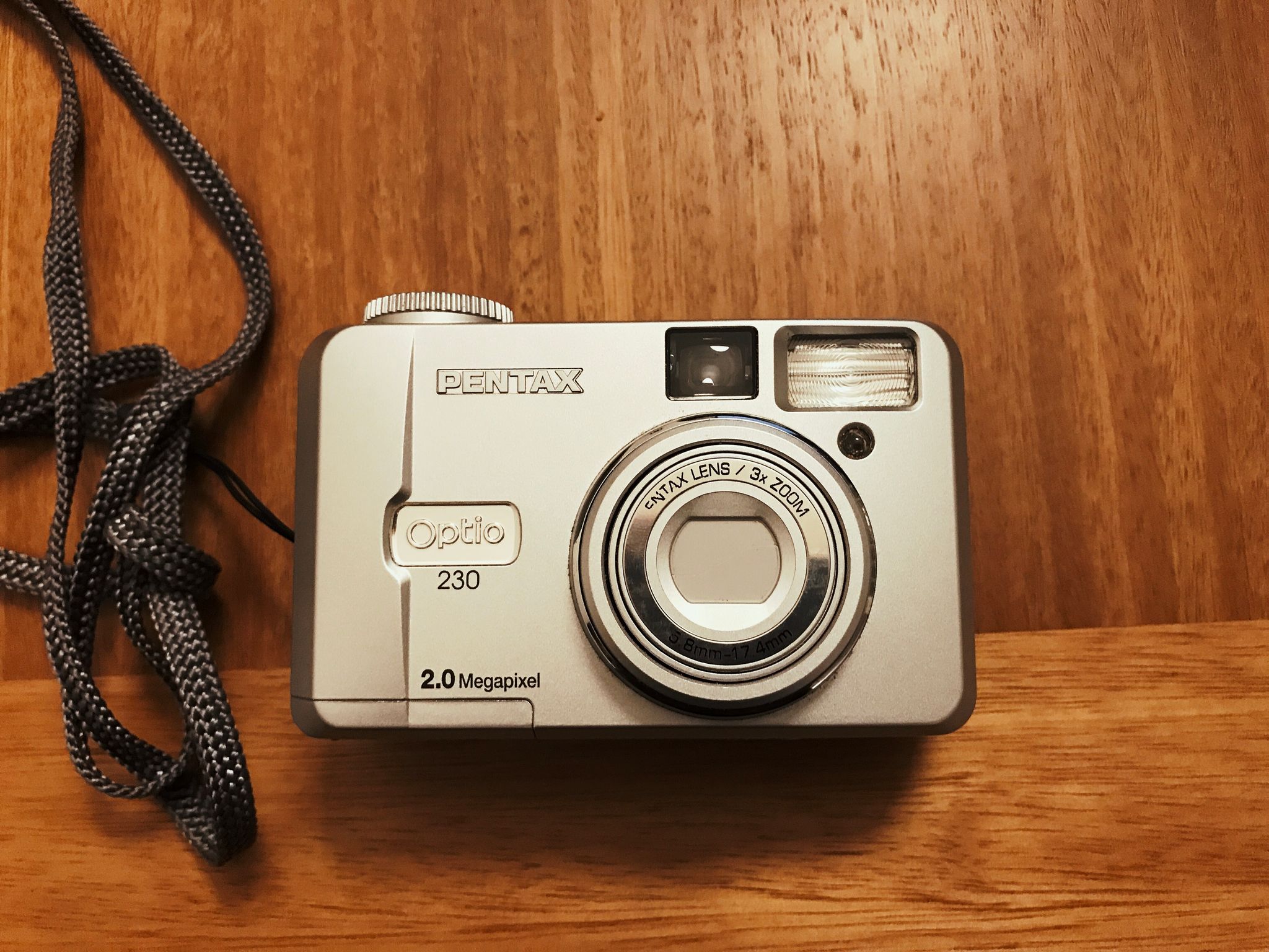 A photo of a Pentax Optio 230 point-and-shoot camera from probably about 2002, with the words “2.0 MEGAPIXELS” emblazoned proudly on the front.