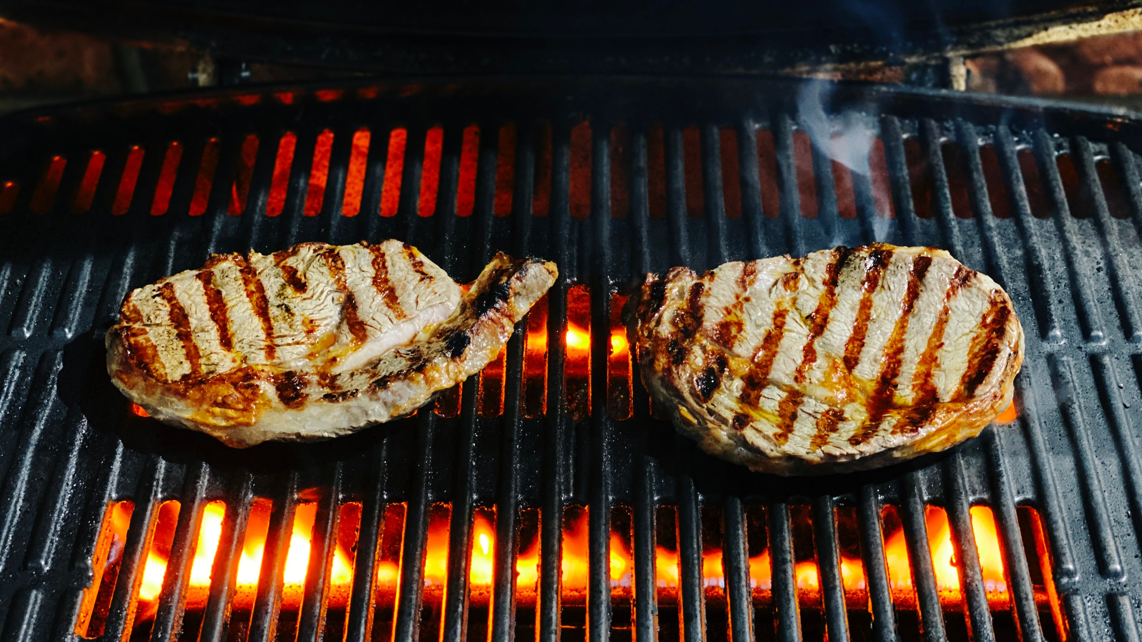 A photo of two seared steaks on a barbecue.