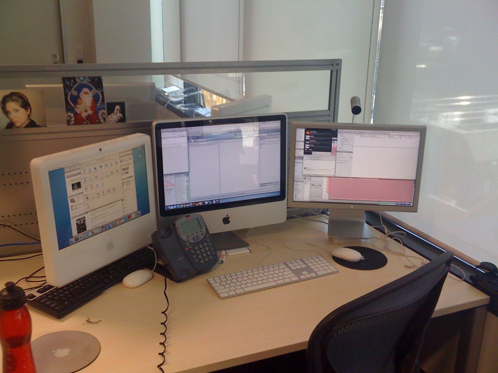 A photo of my desk at work, with a 20" aluminium iMac in the middle, a 20" Cinema Display to the right of it, and a 17" white plastic iMac to the left.