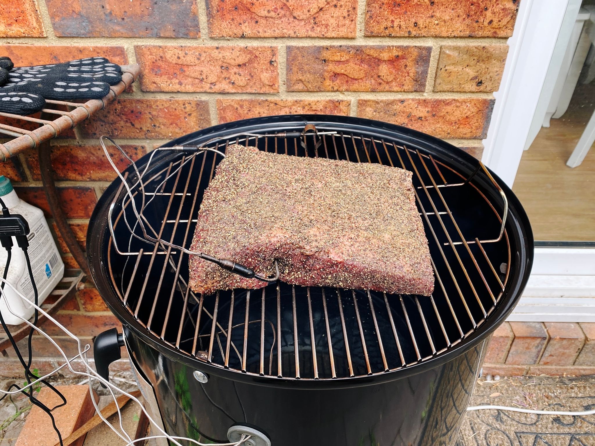 A photo of a beef brisket point sitting on a smoker with two temperature sensors sticking into it.