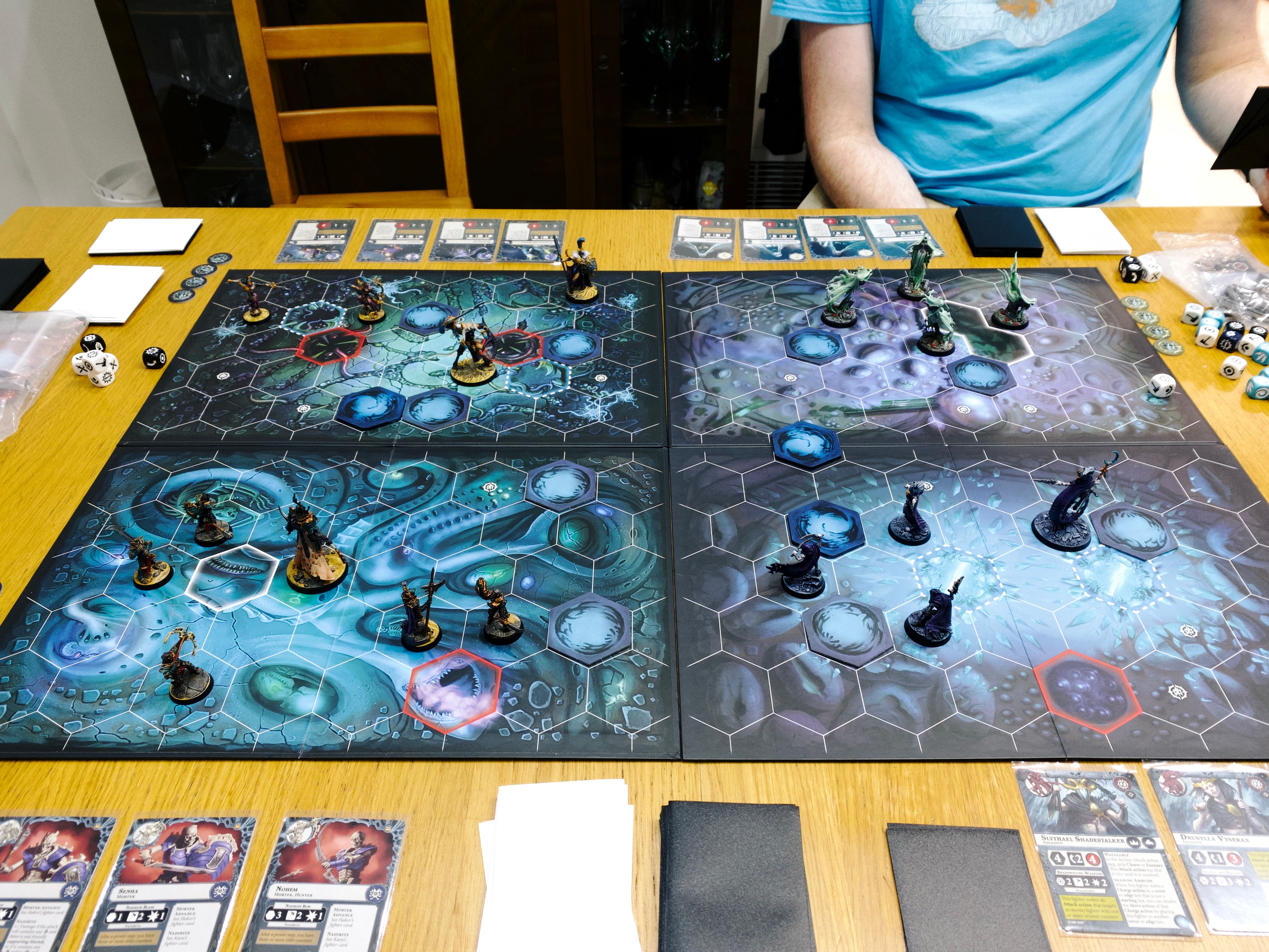 A photo of a game of Warhammer Underworlds. It's a miniature-and-card-based game played on boards with hex tiles on them. On the board were my warband of six armoured skeletons, four spooky ghost-looking things, four lithe elves, and three lightly armoured humans alongside a big S&M-looking goat-man.