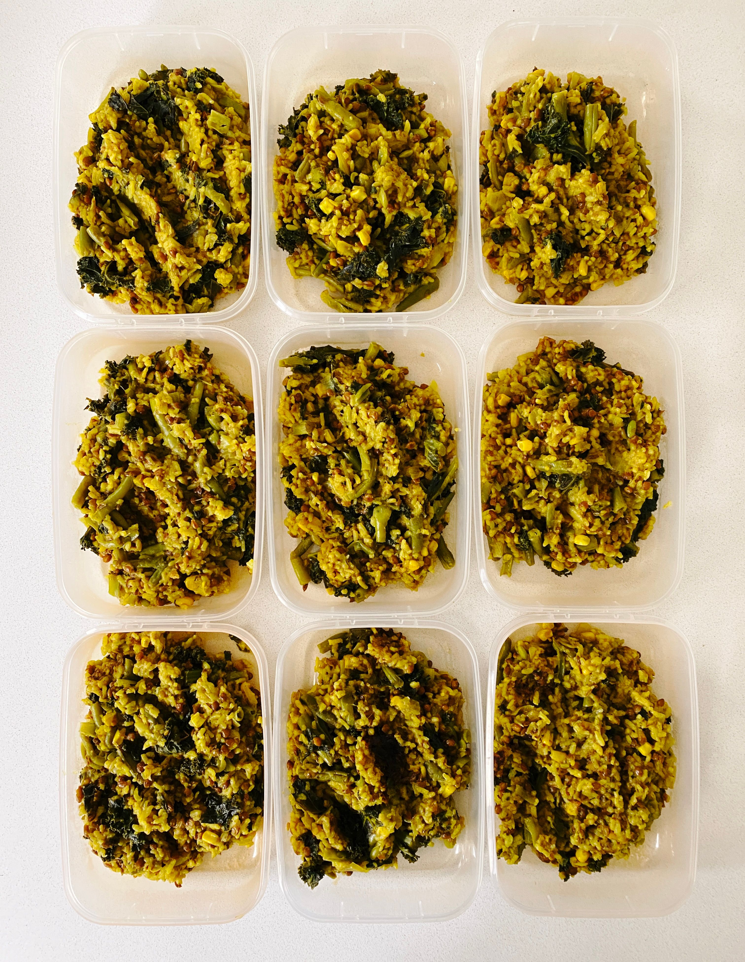 A top-down photo of nine individual Tupperware containers sitting on a white kitchen benchtop. The Persian seasoning has turmeric in it so the rice is VERY yellow.