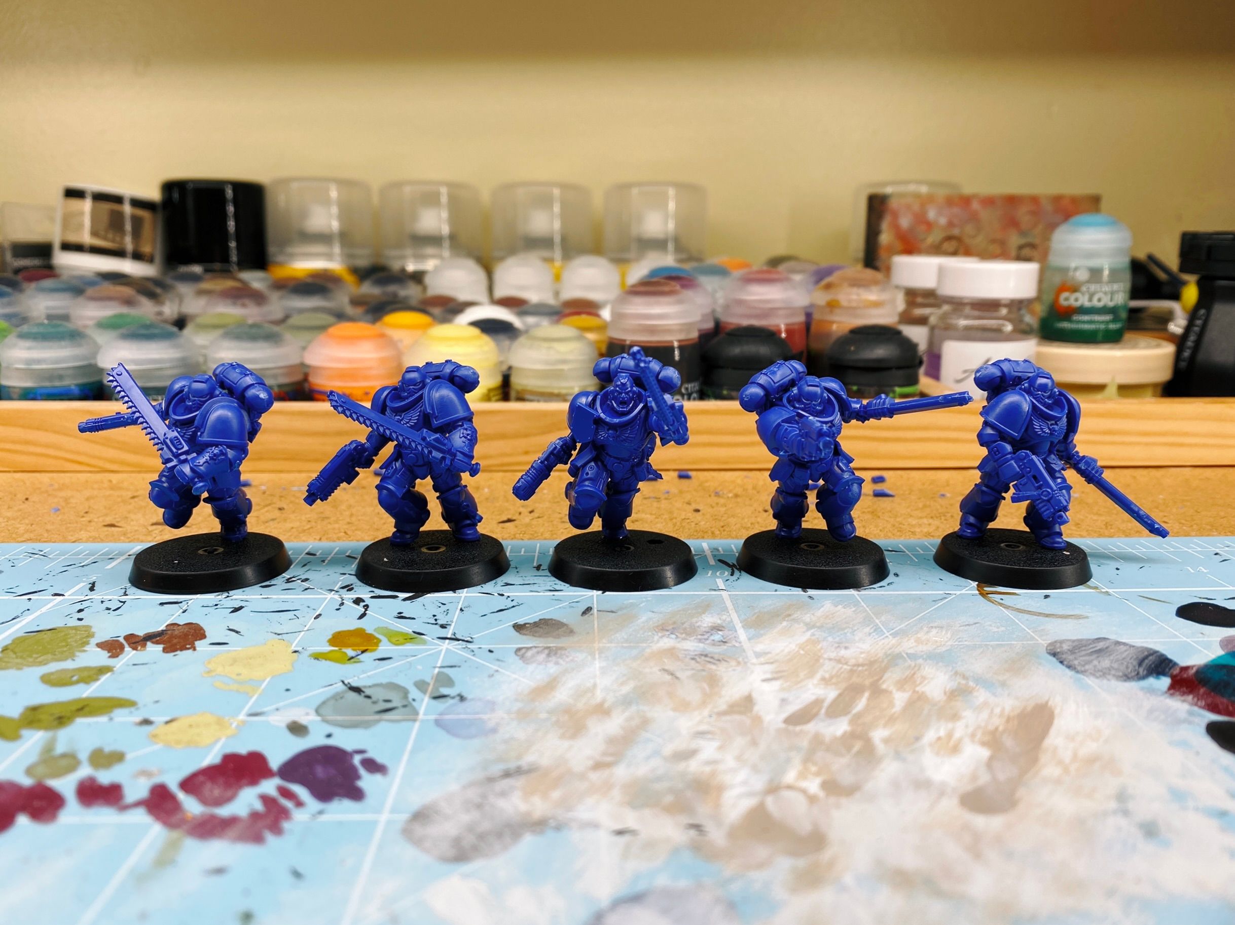 A photo of five Space Marines in bare blue plastic. They're all equipped with chainswords and pistols, and are in various dynamic poses.