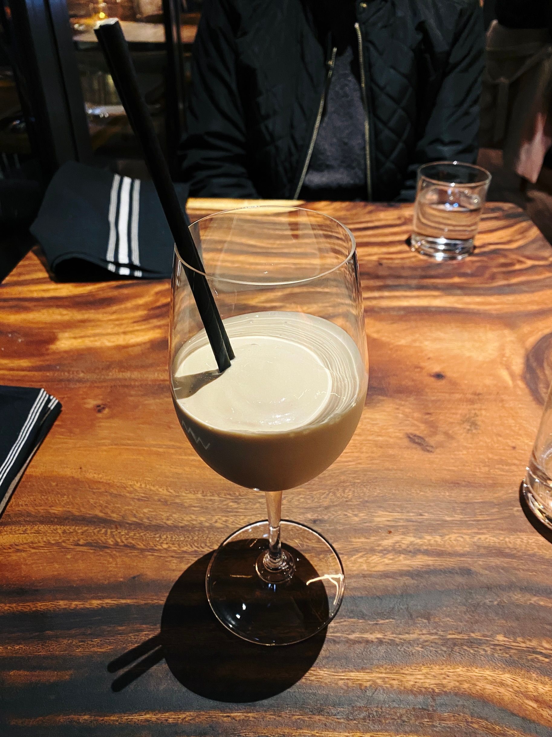 A photo of a big wine glass except instead of wine it has vanilla bean ice cream that's been blended with Kahlua, and has two straws in it.