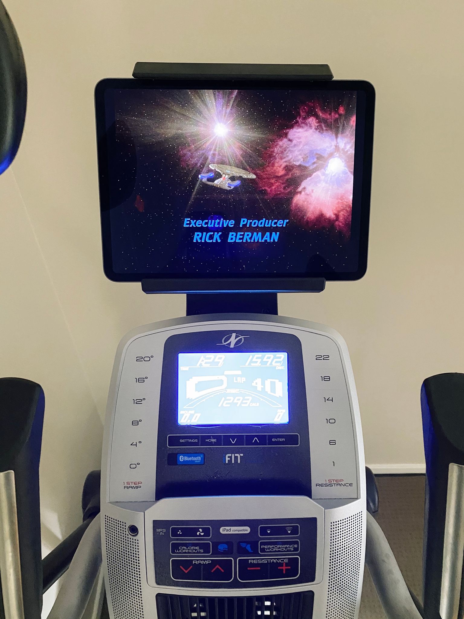 A photo of an iPad sitting on the tablet holder on the top of an elliptical machine, showing the very final closing scene of the Enterprise flying off into the stars. The elliptical display says I'd been going for an hour twenty-nine, 15.92km, and burned 1293 calories.