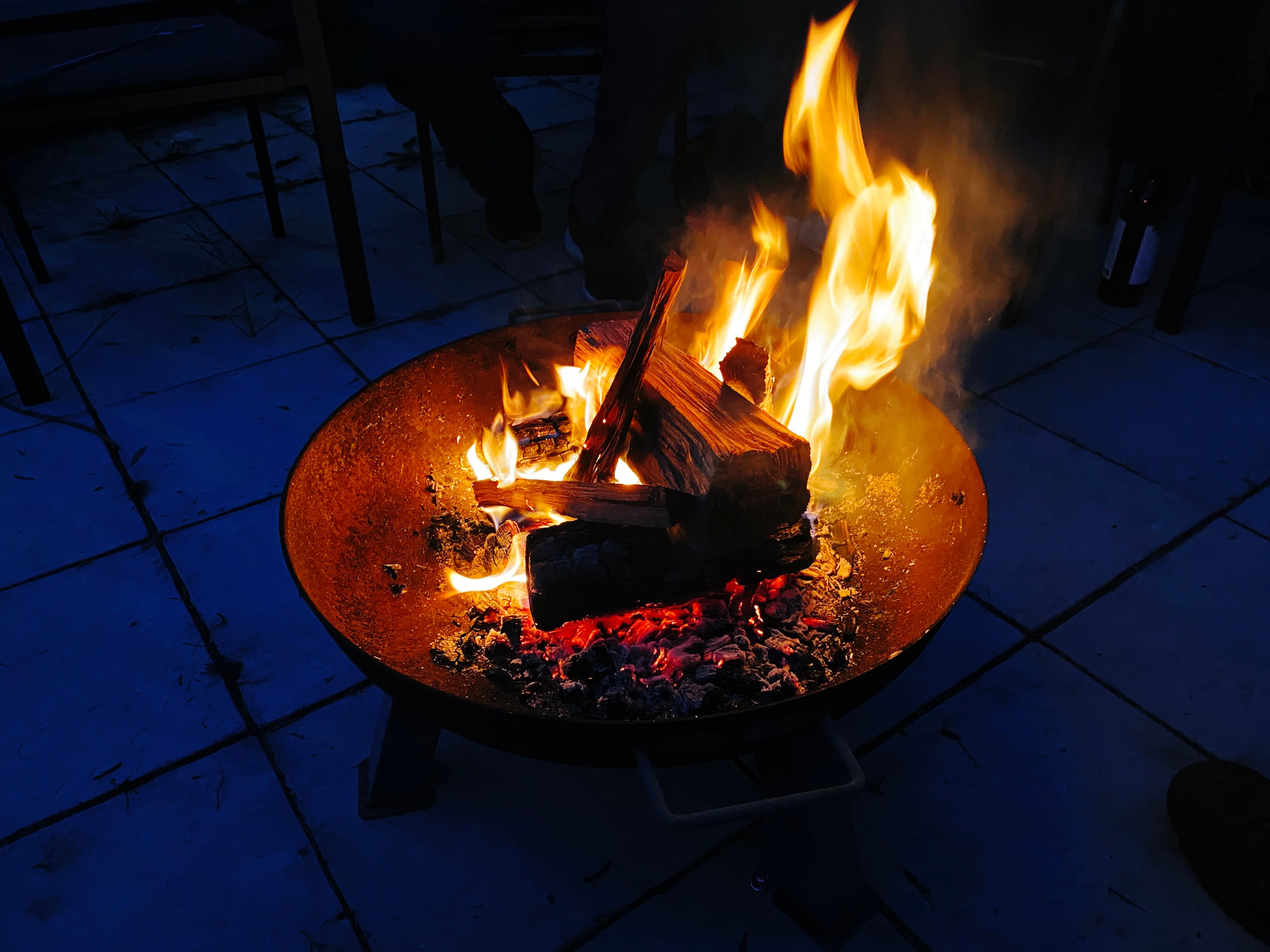 A photo of a raised metal fire "pit" with wood in it and flames merrily burning.