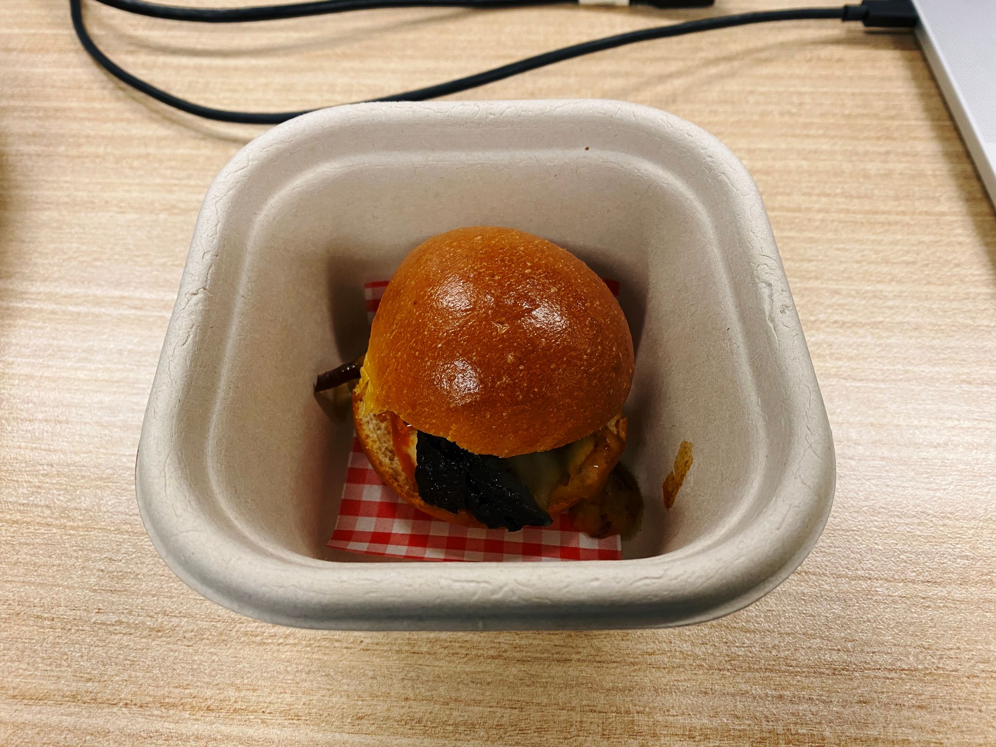 A photo of a tiny little slider sitting in a disposable cardboard container.