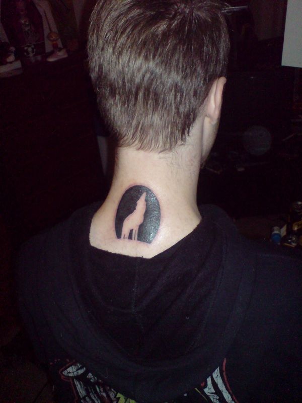 A photo of the back of my neck showing a fresh tattoo of the outline of a wolf with its head raised howling, it's set inside the outline of the moon.