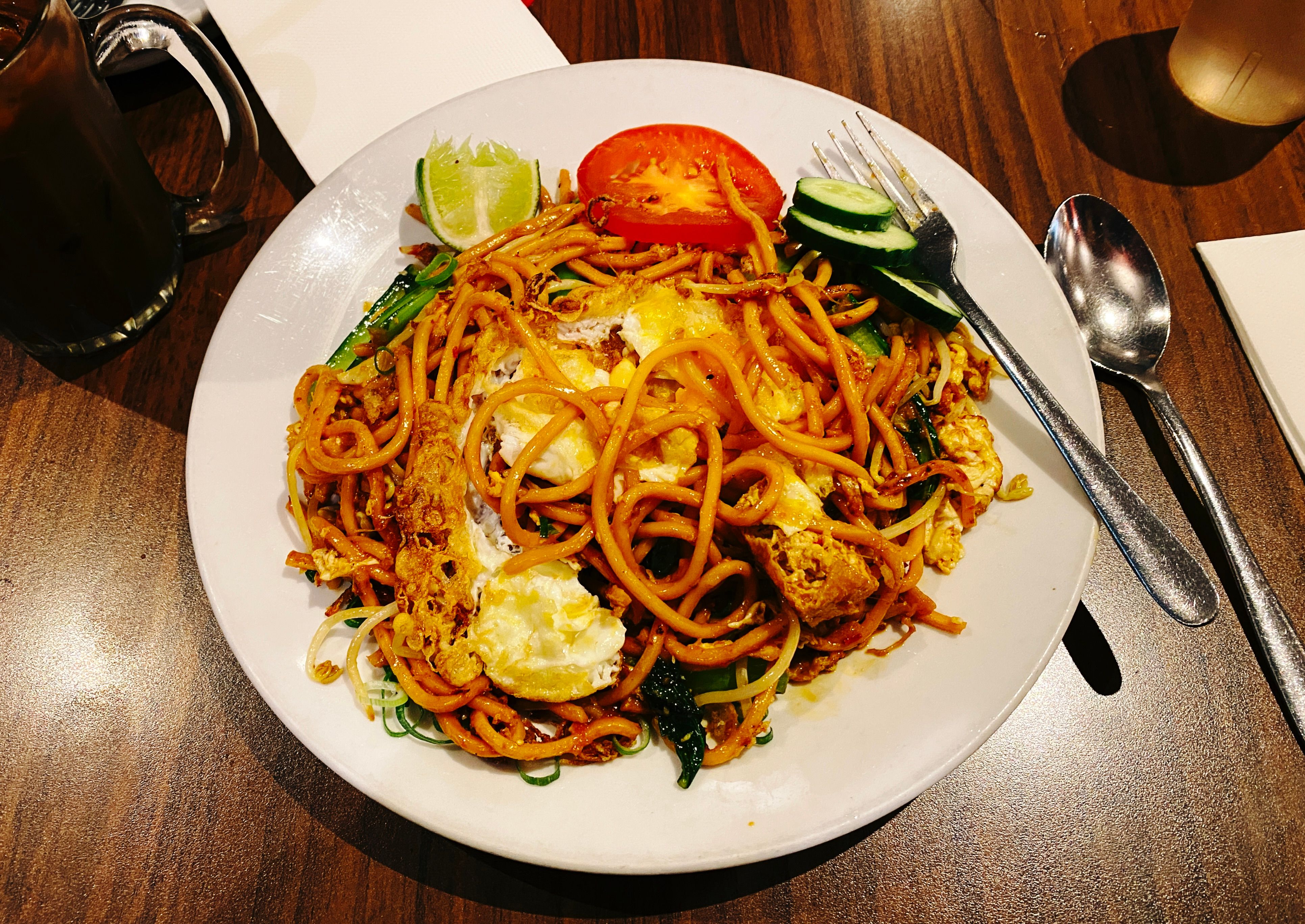 A photo of a plate of mee goreng, a noodle dish, that has a fried egg mixed into it.