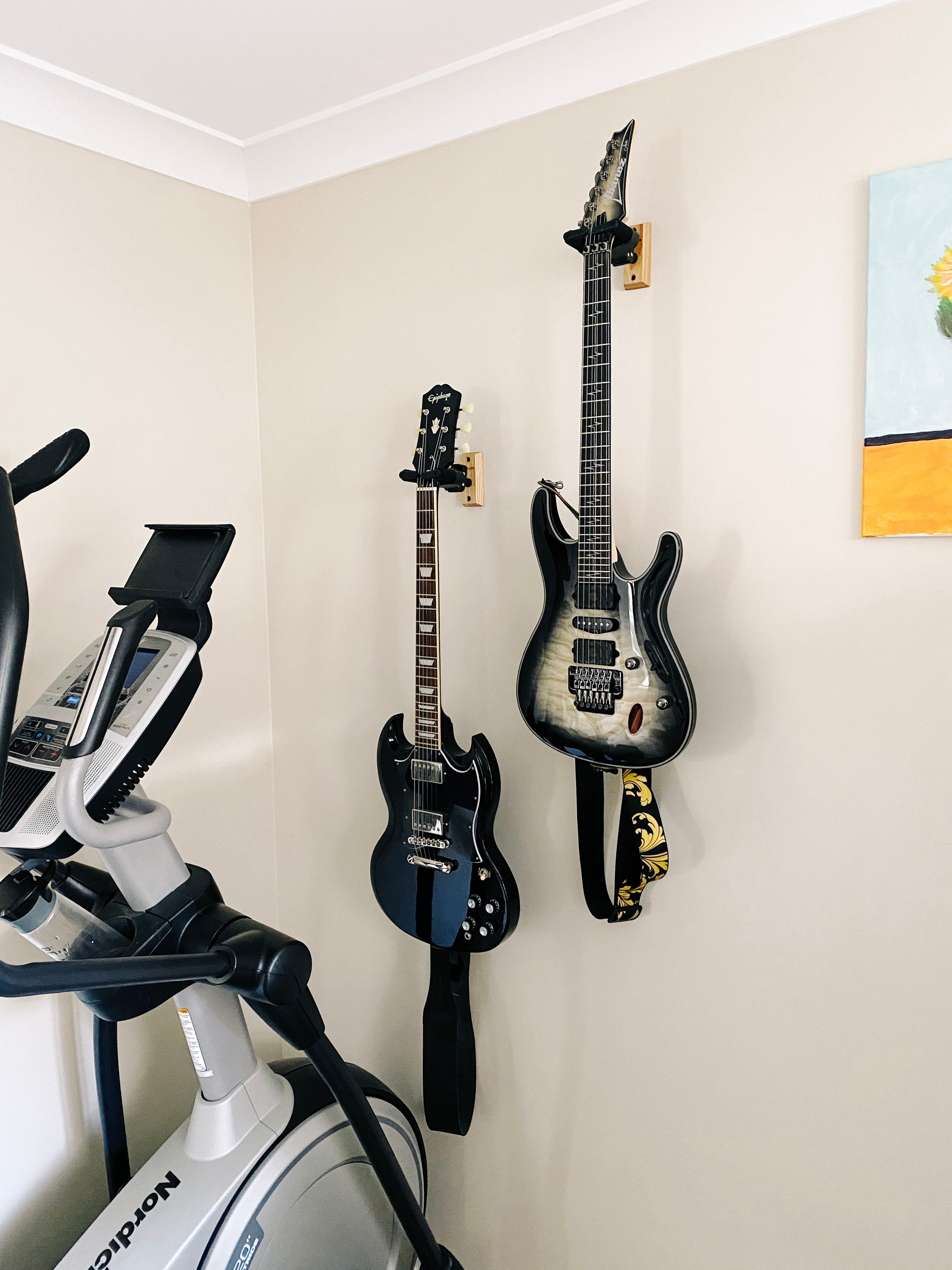 A photo of two electric guitars hanging from wall mounts.