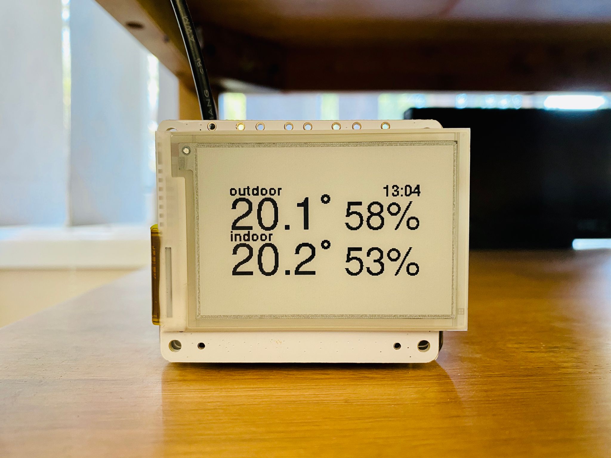 A photo of a small e-ink display showing indoor and outdoor temperature and humidity, but the information is sized for the old 2" display and it looks very silly now.