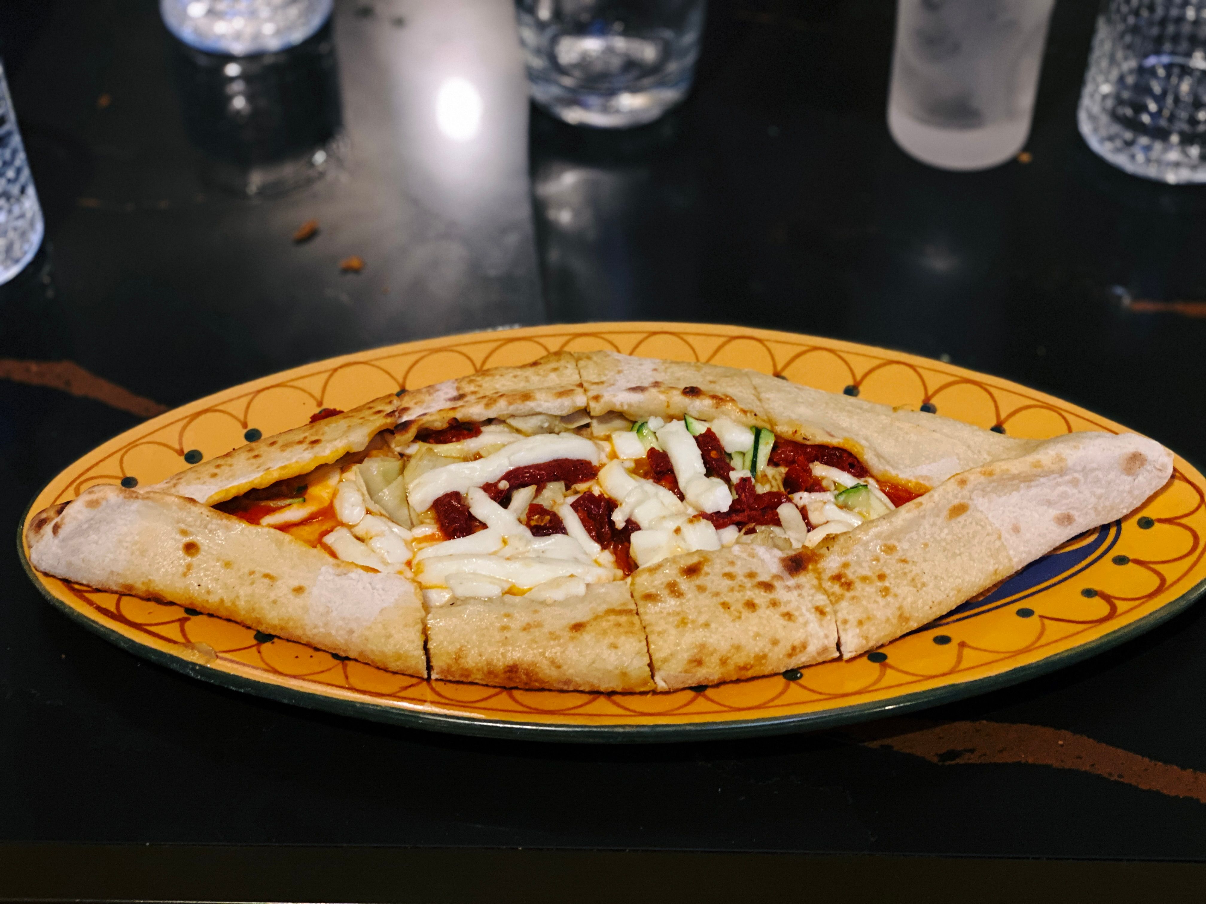 A photo of the spiced halloumi pizza, which is actually Turkish pide with a tomato sauce inside it and strips of halloumi and what I think was sun-dried tomato.