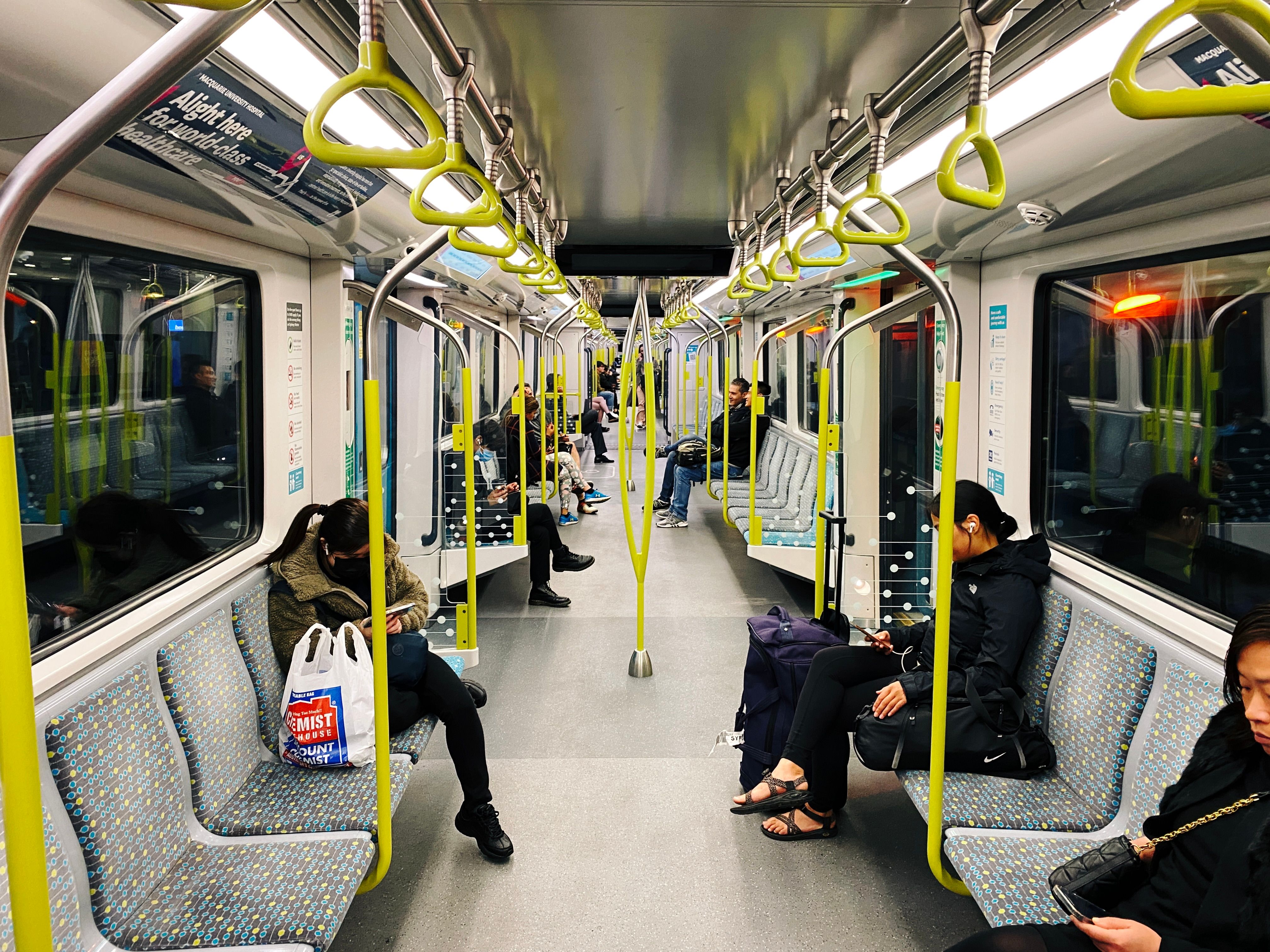 A photo looking down the middle of a Sydney Metro train. It's a single-deck subway-style train with seats on either side facing the middle.